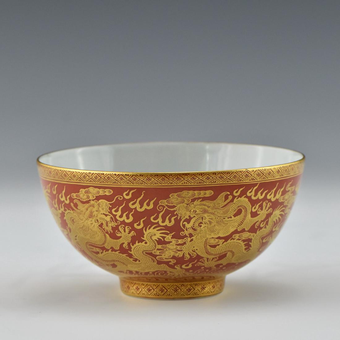 GILT DRAGON RED PORCELAIN BOWL: Chinese Qing Dynasty porcelain delicately potted in a simply deep vessel, with rounded cavetto gently rising the sides toward flat rim, raised upon a concaved foot base. The exterior decorated with gi