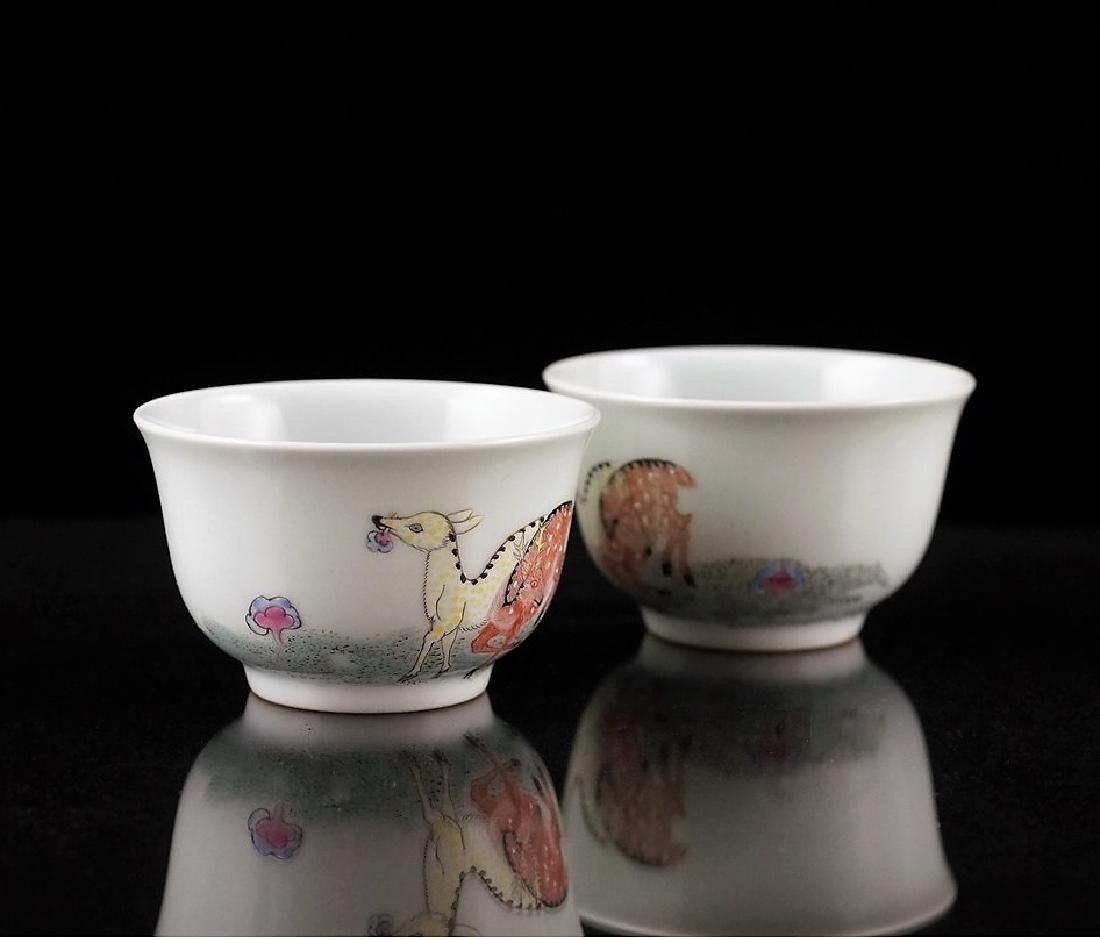 PAIR OF FAMILLE ROSE DEER MOTIF PORCELAIN WINE CUPS: Finely potted Chinese porcelain unto a deep vessel form, with rounded cavetto rising a steep sides toward slightly flared rim, upon a ring footed base. The exterior decorated in soft famille rose hand