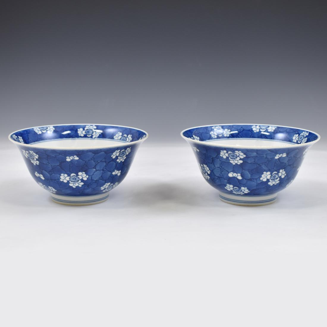PAIR OF BLUE GLAZED FLORAL MOTIF BOWLS: Pair of Chinese porcelain bowls. Deep curvature flaring upward to form the rim, with a slightly raised footing. The rim has a double blue ring around the outer edge. The exterior is adorned with hand-