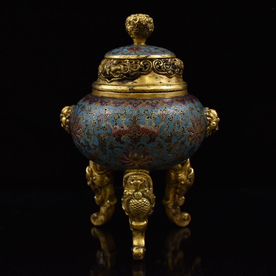 GILT BRONZE & CLOISONNE COVERED TRIPOD CENSER: The Chinese gilt bronze covered tripod censer repoussed in a spherical body of the censer is decorated in enameled cloisonne works with a design of scrolling leafy tendrils suspending lotus blossoms o