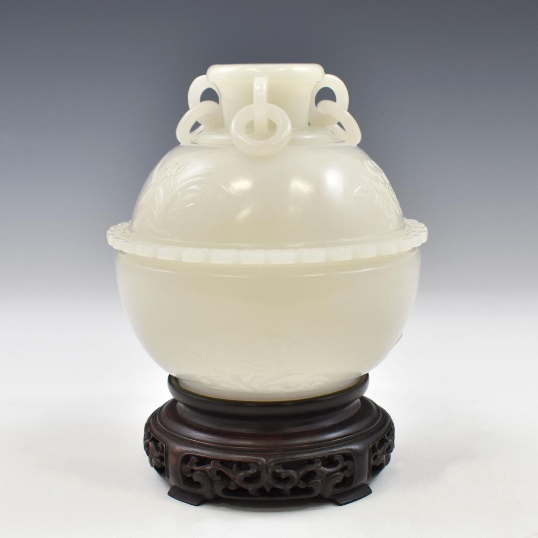 FINE CARVED WHITE JADE COVERED CENSER ON STAND: The generous portion nephrite jade finely carved unto simply rounded shape body, with wide opening and banded rim. The simply flaring finial everted from the dome lids flanked with four loops, each ho