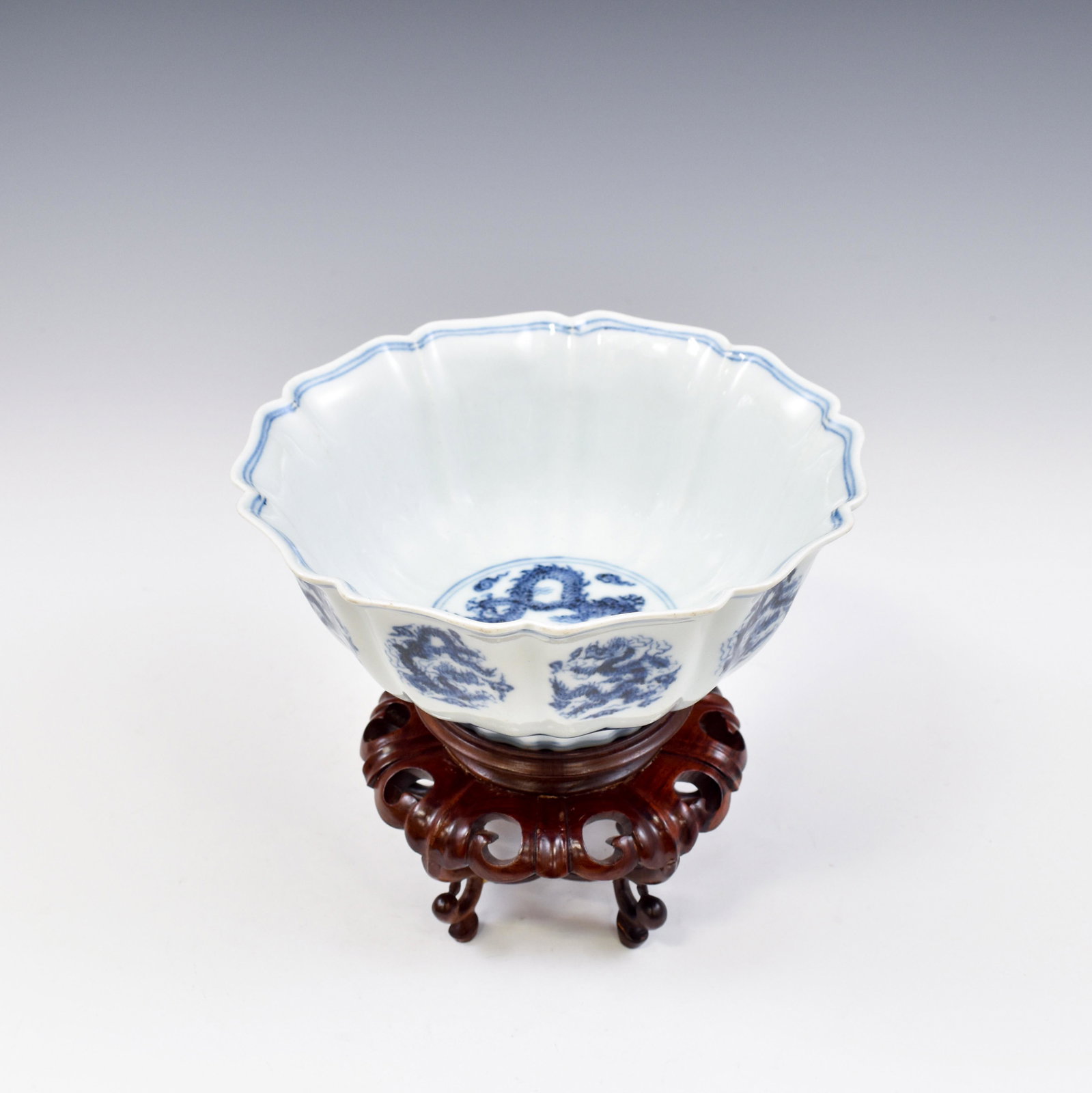 XUANDE BLUE AND WHITE LOBBED BOWL: Dimensions: 3-3/8" H x 7-3/4" W Stand: 3-1/8" H Chinese Ming Dynasty Period, Xuande blue and white Dragon porcelain bowl. Thick potted, shallow body, with a flaring opening lip, raised on round slight