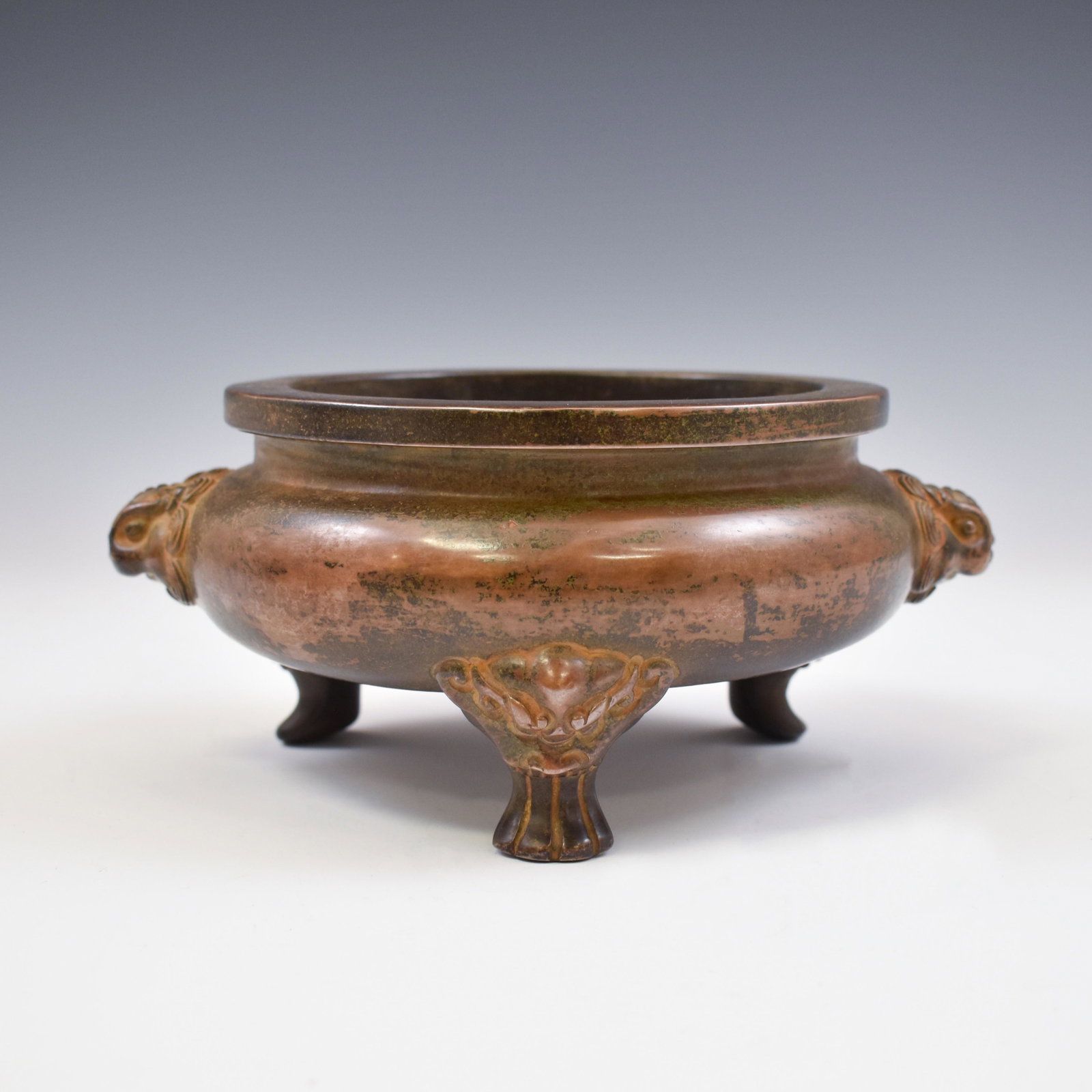 XUANDE BRONZE TRIPOD CENSER: The Chinese Ming bronze tripod censer. Carved in shape of a tapered globular body, with wide open mouth carved , raised on the three conical low legs, with banded rim on the neck. Two Lion masks suspe