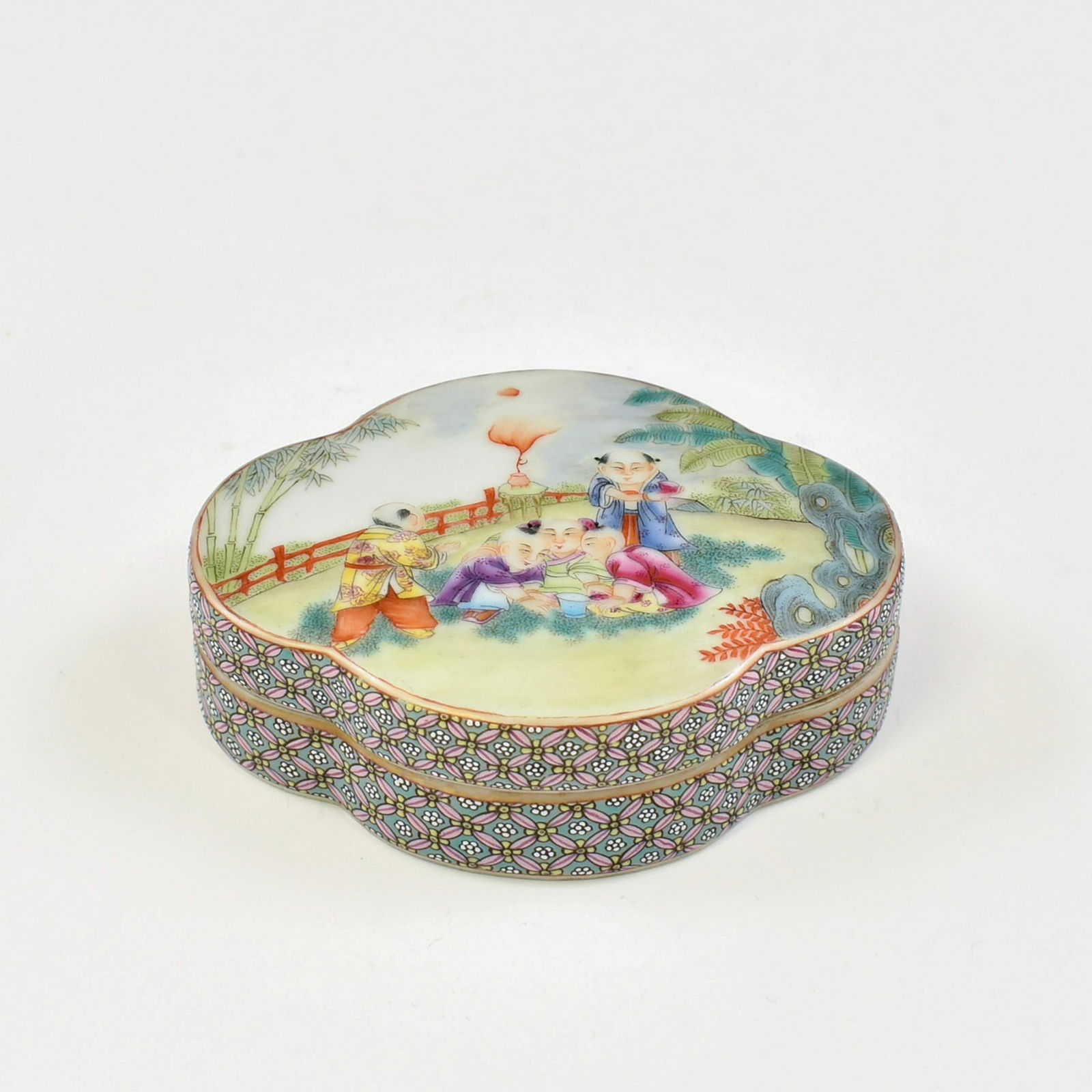 QIANLONG FAMILLE ROSE BOYS MOTIF FLORI FORM BOX: Chinese Qing Dynasty Qianlong famille rose boys motif quatre-foil flori form shaped porcelain lidded box. The Under-base bears a reign mark, a six underglaze blue seal script characters reign mark, Ma