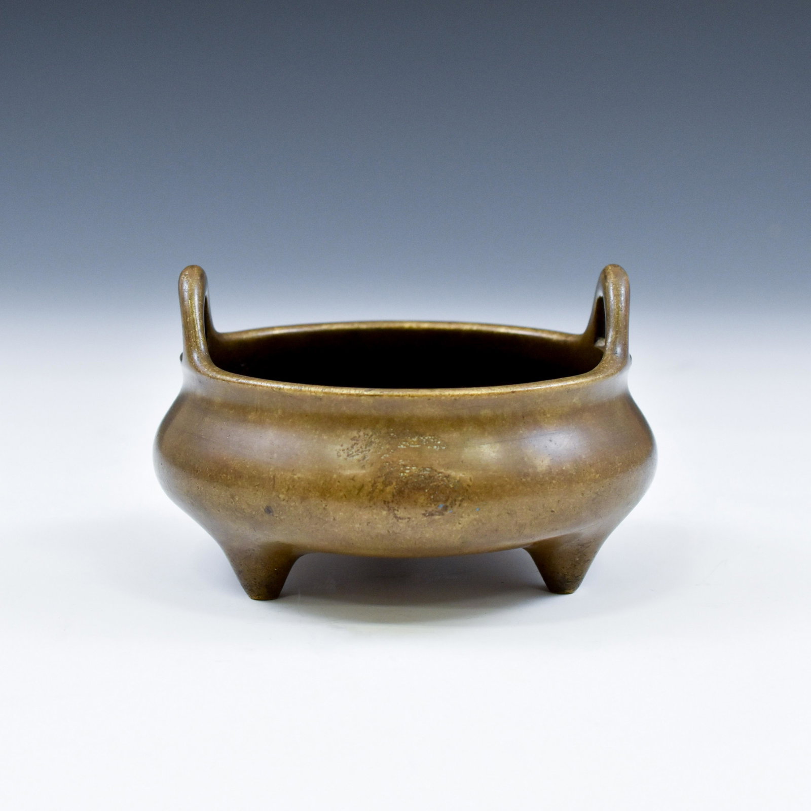CHINESE MING PERIOD TRIPOD BRONZE CENSER: 15th Century antique Chinese Ming Dynasty bronze censer, cast in compressed globular form, short neck to flat open wide rim, raised on three conical short legs, with two loop handles vertically everte