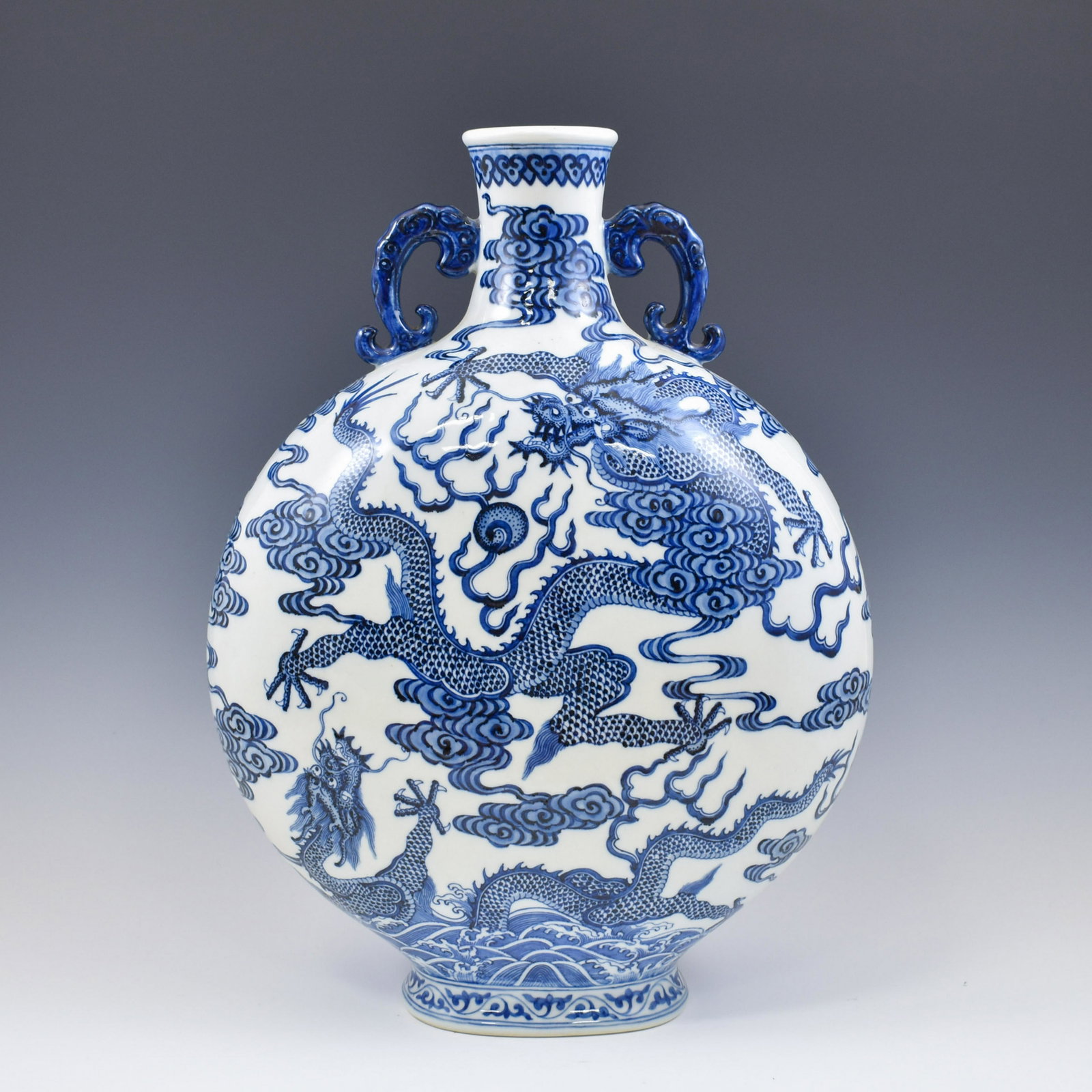 QIANLONG BLUE & WHITE DRAGON MOON VASE: A large moon flask vase. Its shape means embracing the moon and consists of a circular flattened body signifying the moon, a flat base, tubular neck and two applied handles which arch gracefully, desc
