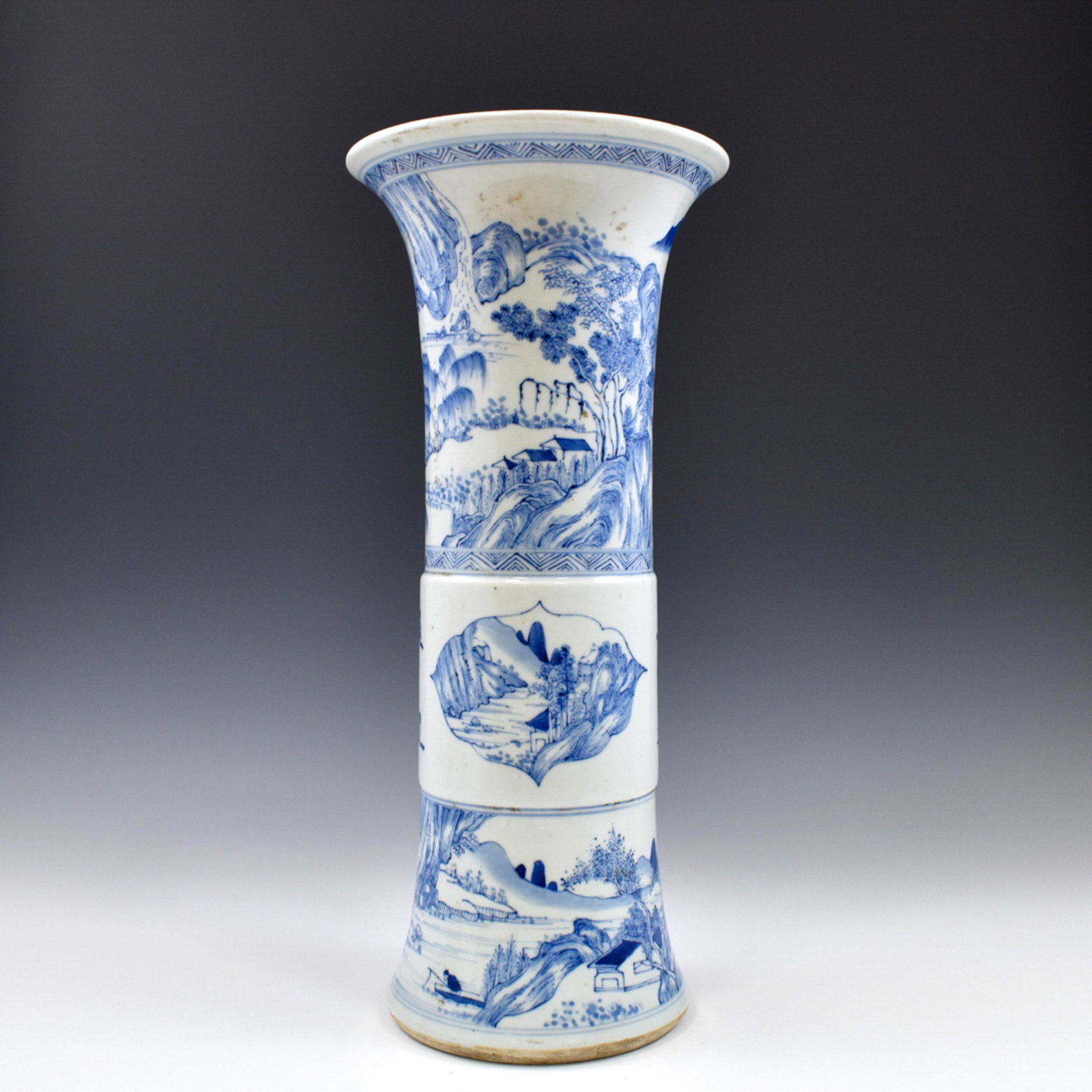 MING BLUE & WHITE LANDSCAPE MOTIF GU VASE: The vase potted in a Chinese Ming porcelain traditional Gu shape. The beaker having baluster shaped body, with slightly arise belly, trumpet-shaped neck are painted in blue underglaze depicted a lands
