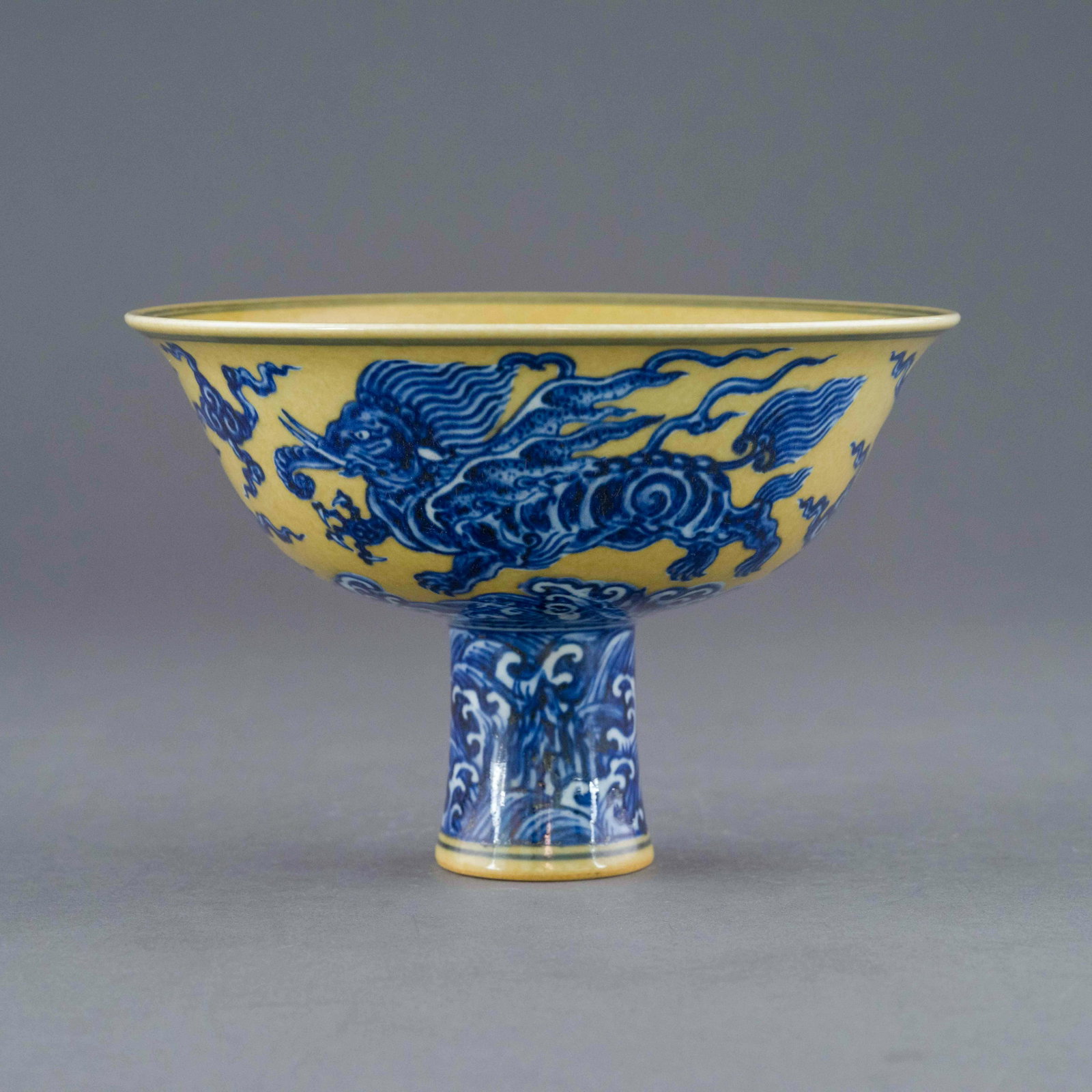 XUANDE BLUE QILIN FAMILLE JAUNE HIGH BOWL: Dimensions: 4.75in H x 7in W x 7in D Chinese Ming Dynasty Period Xuande blue qilin famille jaune high bowl. The porcelain potted with a shallow body, of a shallow vessel, broad wide cavetto, with a st