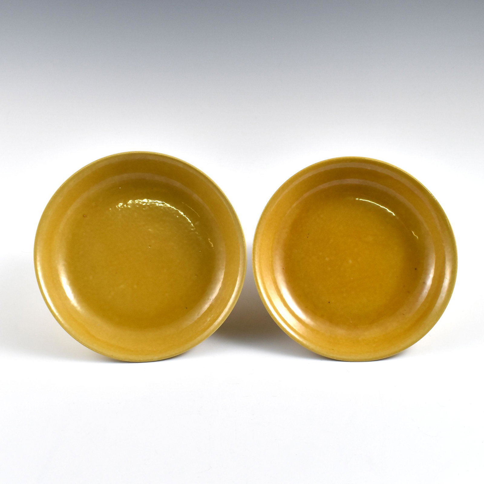 PR. Ming Wanli Famille Jaune monochrome plates: Dimensions: 1-1/4" H x 7-7/8" Dia. (each) Pair of Chinese Ming Dynasty Period, Wanli Famille Jaune monochrome plates. Potted in shallow vessel form, thick and large, slight deep, with broad wide centr