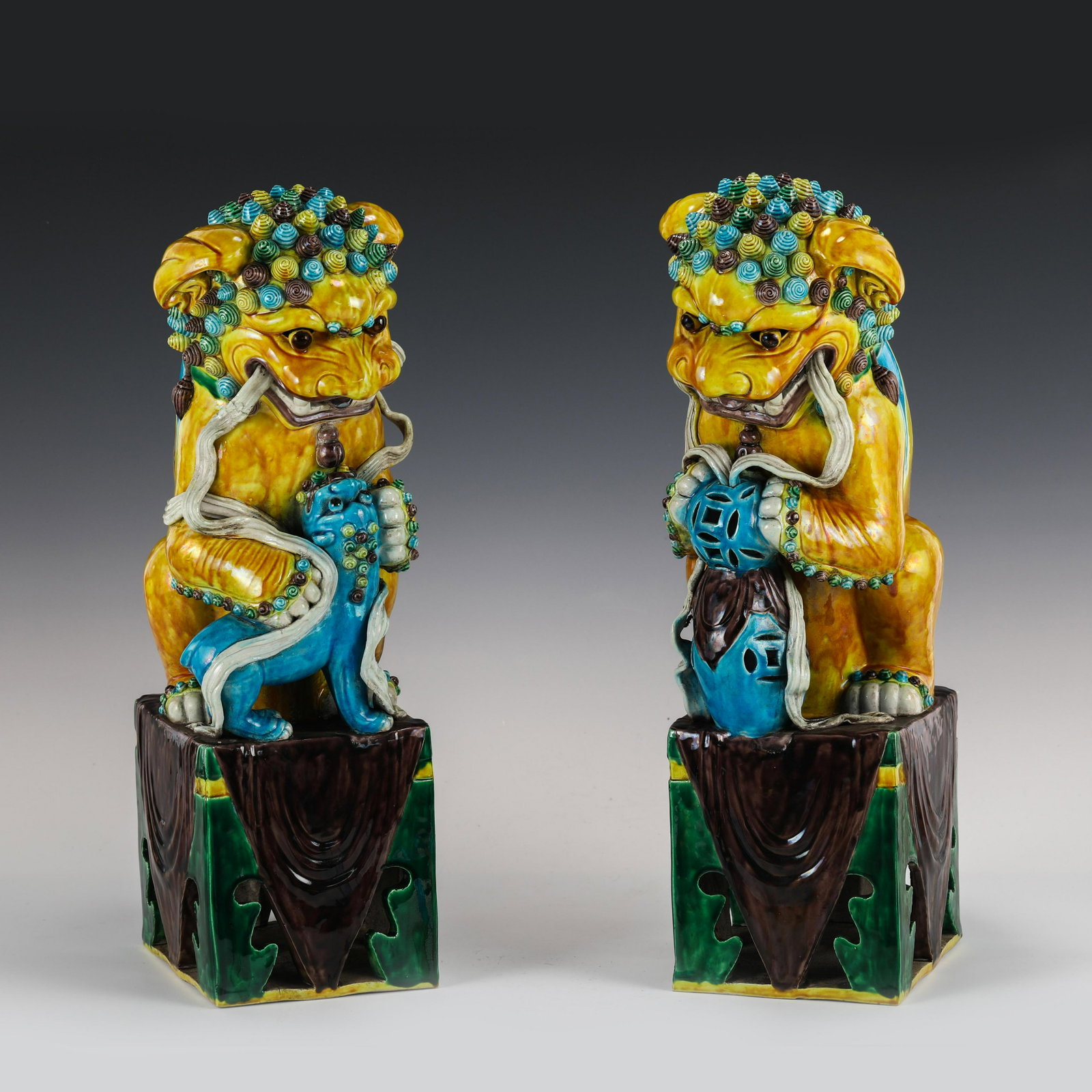 PAIR SANCAI GLAZED PORCELAIN FU LION STATUES: Dimensions (cm): Height: 51 Width: 21 Length: 16 Pair of Chinese Ming Dynasty Period Sancai glazed Porcelain Fu Lion statues. A Chinese Fu Lions made of porcelain in yellow glazed. Stands with a treas