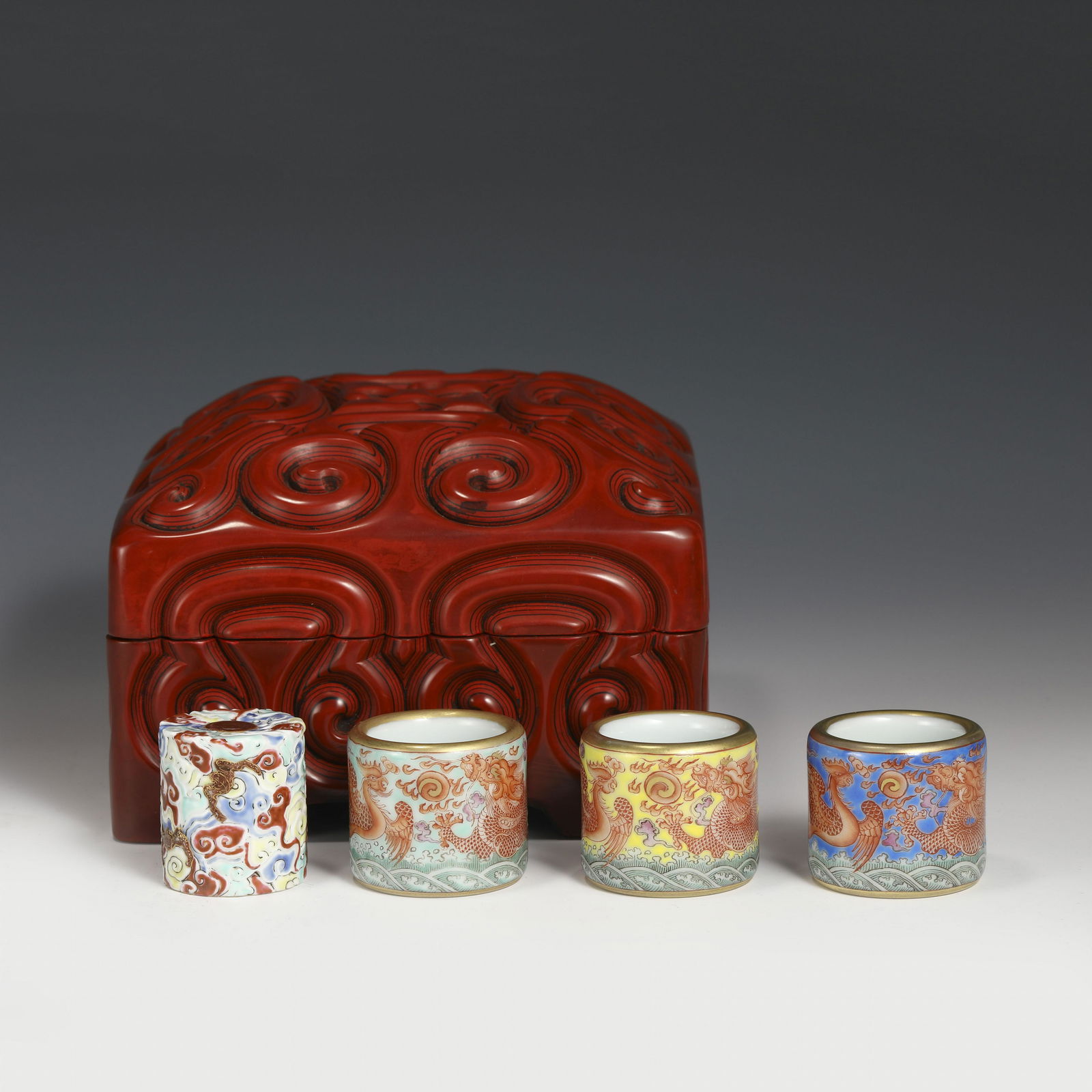 SET O 4 PORCELAIN ARCHER RINGS IN BOX: Dimensions: Width: 4.5cm, Height: 3.5cm Set of Four Chinese Qing Dynasty Qianlong Porcelain Thumb Rings in Hardwood Box. Potted in round open lip, short cylindrical body with round pit on the center e