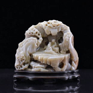 CHINESE CARVED JADE BOULDER MOUNTAIN ON STAND: Dimensions: 120.65mm H x 139.7mm W ; (only Stand): 1"H Weight: 1451.8g The grayish-celadon nephrite jade expertly carved resembled a grotto, with a sage seated beneath the shading tree out