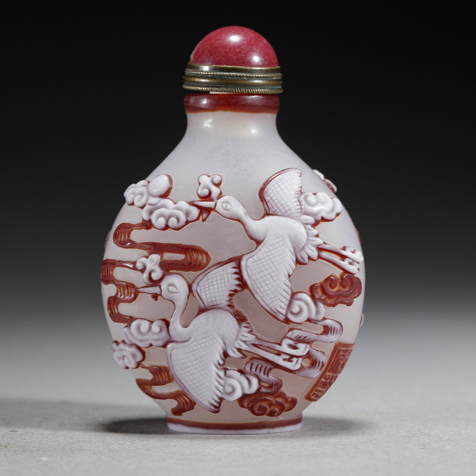 A PEKING GLASS OVERLAY SNUFF BOTTLE: Dimensions: 5 cm L x 3 cm W x 7.5 cm H x Weight 64 gram. Of flatten ovoid shape, decorated flying cranes at the exterior, with matched stopper.
