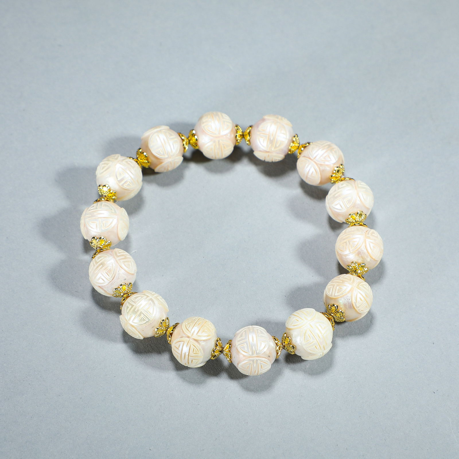 CHINESE CARVED PEARL SHOU BEAD BRACELET: Dimensions: ???L. 1.4 cm. Weight 40 grams. This elegant Chinese bracelet is composed of lustrous, pale pink pearls, each intricately carved with the ?shou? (longevity) symbol, alternating with