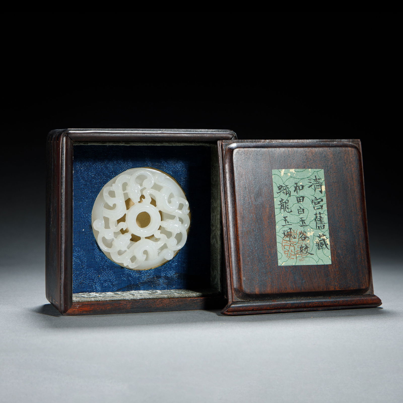 CHINESE HETIAN JADE BI DISC: Dimensions: L. 5.5 cm. H. 1.5 cm. Weight 46 grams. This exquisite Chinese Hetian jade bi disc features intricate openwork carving of sinuous chilong dragons, rendered in luminous white nephrite