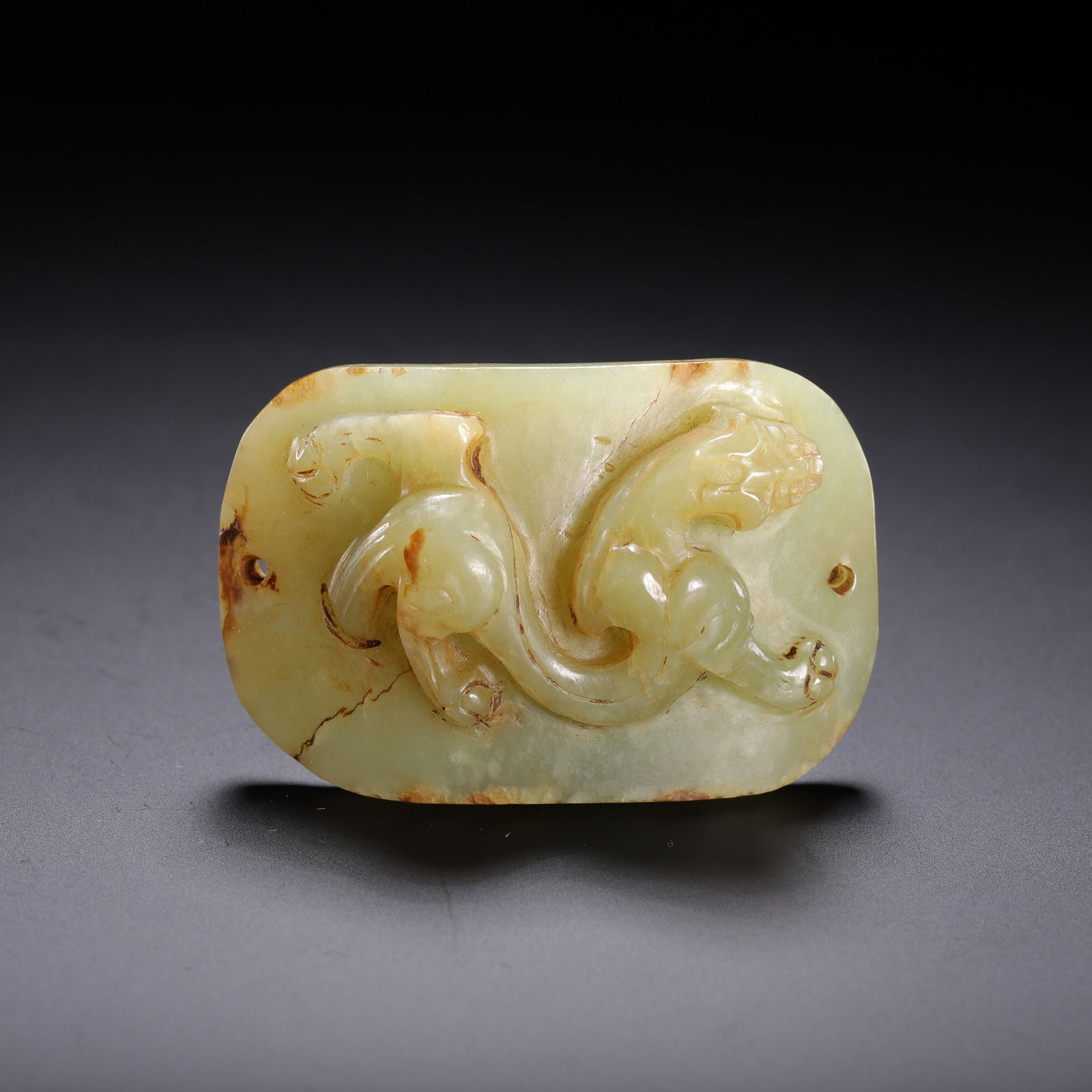 CHINESE ARCHAIC JADE PLAQUE: Dimensions: L. 5 cm. W. 3.5 cm. Weight 40 grams. This elegant Chinese archaic jade plaque features a low-relief carving of a sinuous chilong dragon, its dynamic form following the natural contours of