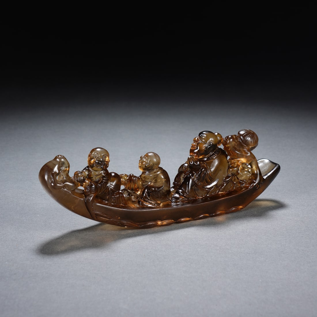 CHINESE ROCK CRYSTAL BOAT GROUP: Dimensions: 13x3x4.5 cm. Weight 122 grams. This charming Chinese rock crystal carving depicts a group of figures seated in a slender boat, rendered from translucent smoky quartz with warm, honeyed ton