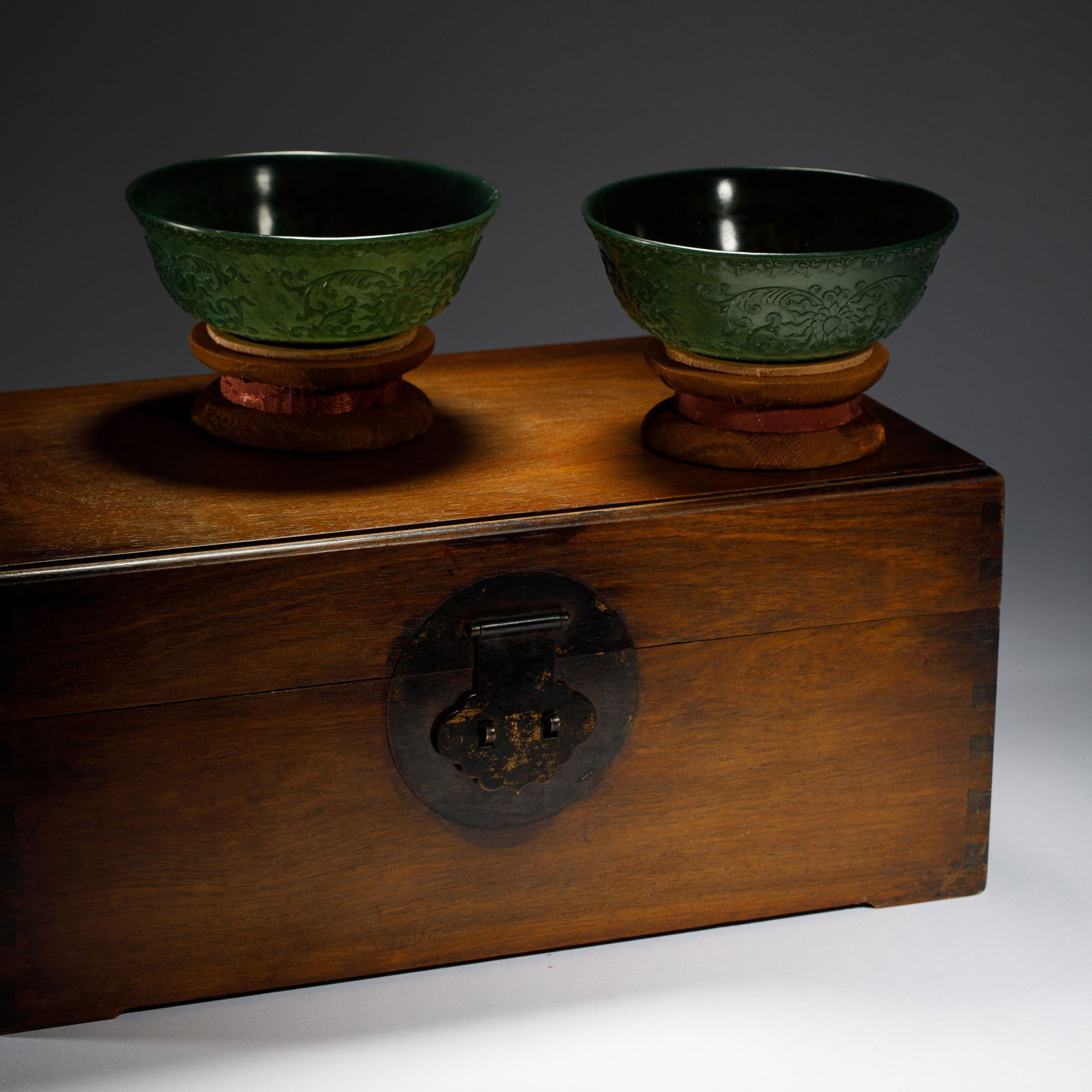 CHINESE HETIAN GREEN JADE BOWL PAIR: Dimensions: L. 12.9 cm. H. 5.2 cm. Weight 215 grams. This elegant pair of Chinese Hetian green jade bowls features a deep, rich green hue and a delicate, translucent finish. Each bowl?s exterior