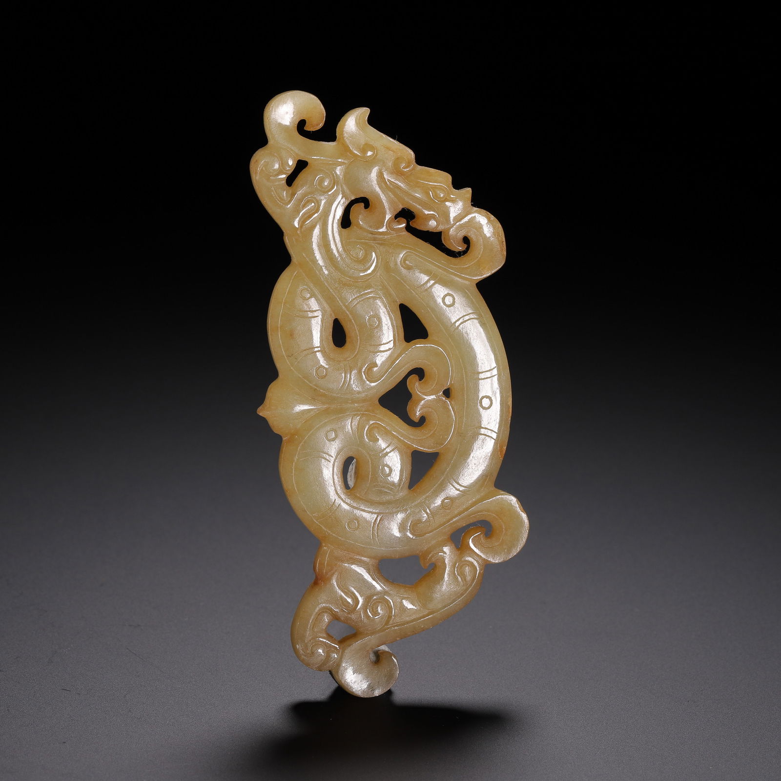 CHINESE ARCHAIC JADE DRAGON PENDANT: Dimensions: L. 10.5 cm. W. 4.5 cm. Weight 40 grams. This exquisite Chinese archaic jade pendant is carved in an openwork design of a sinuous coiling dragon, its body adorned with fine incised lines th