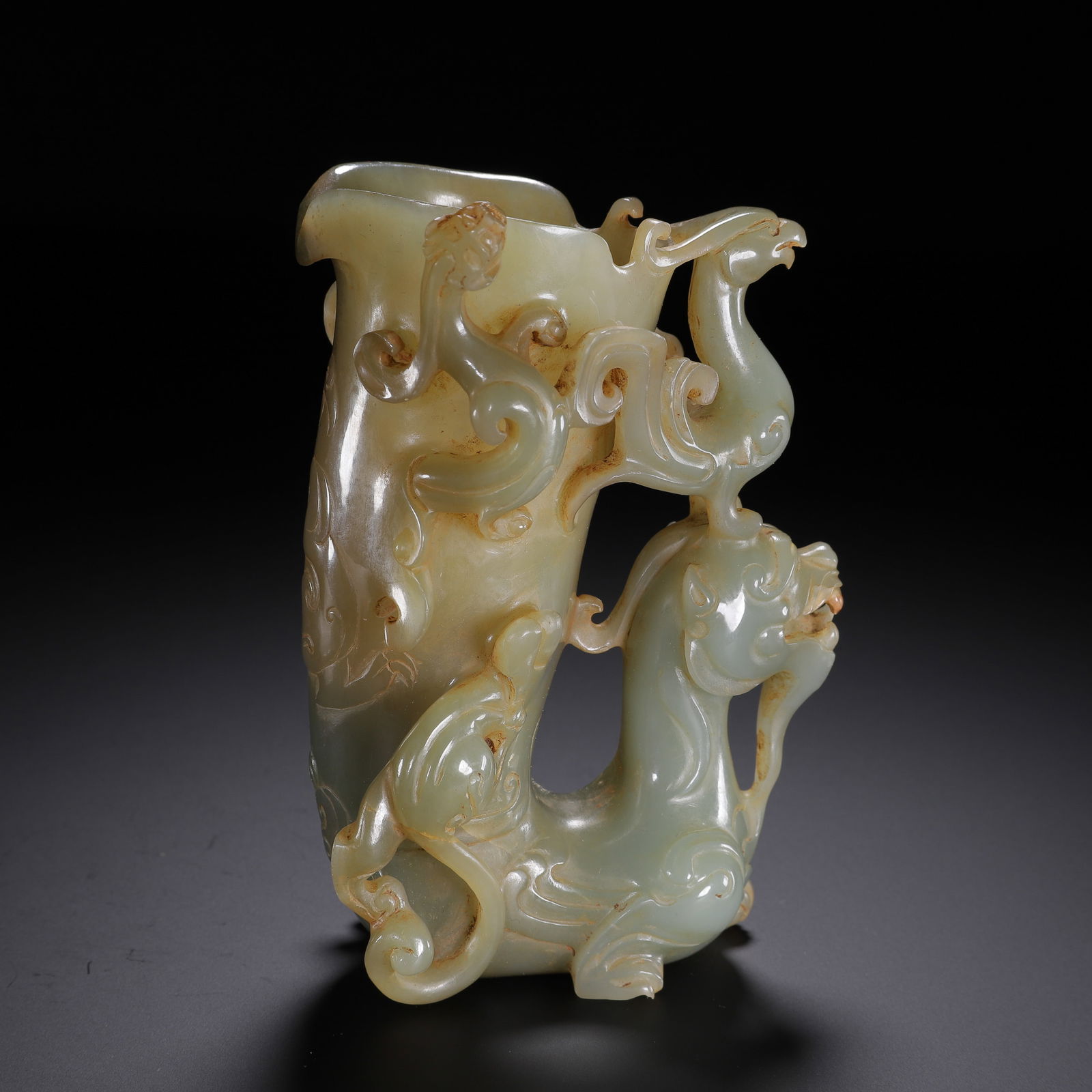 CHINESE ARCHAIC JADE LIBATION CUP: Dimensions: L. 8 cm. W. 7.5 cm. H. 12 cm. Weight 390 grams. This magnificent Chinese archaic jade libation cup is carved from translucent celadon stone with warm russet inclusions, featuring a