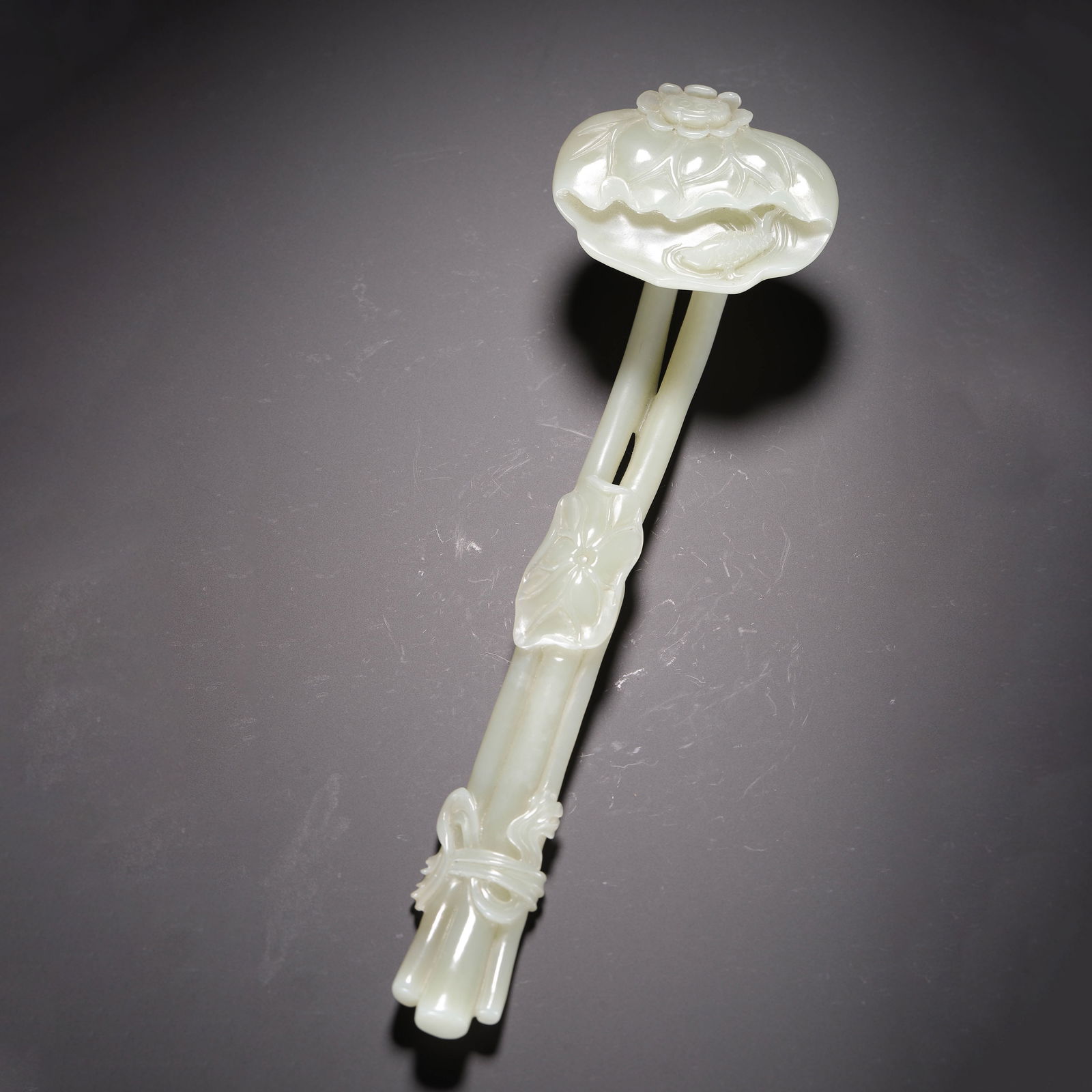 CHINESE WHITE JADE RUYI SCEPTER: Dimensions: L. 26 cm. Weight 210 grams. This elegant Chinese ruyi scepter is carved from translucent white Hetian jade, featuring a lotus-form head and a handle designed as bound lotus stems, symboliz