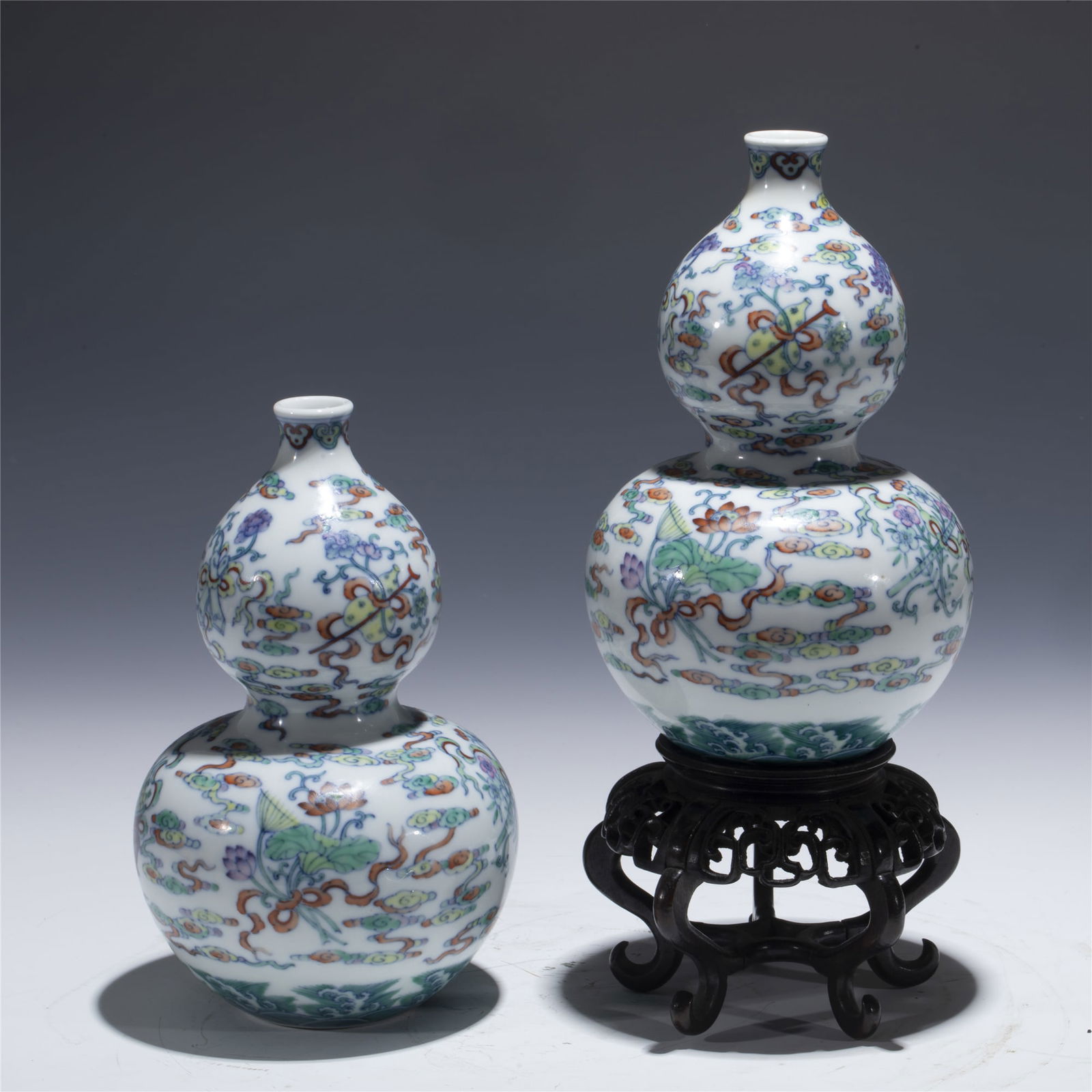 PAIR OF QING QIANLONG DOUCAI GOURD BOTTLES: Dimensions: length: 11. 5 cm, Width: 11. 5 cm, Height: 18. 8 cm Pair of Chinese Qing Dynasty Qianlong Doucai Porcelain Gourd Bottle Vases On Hardwood Stand. Potted in a shape of double gourd resemblan