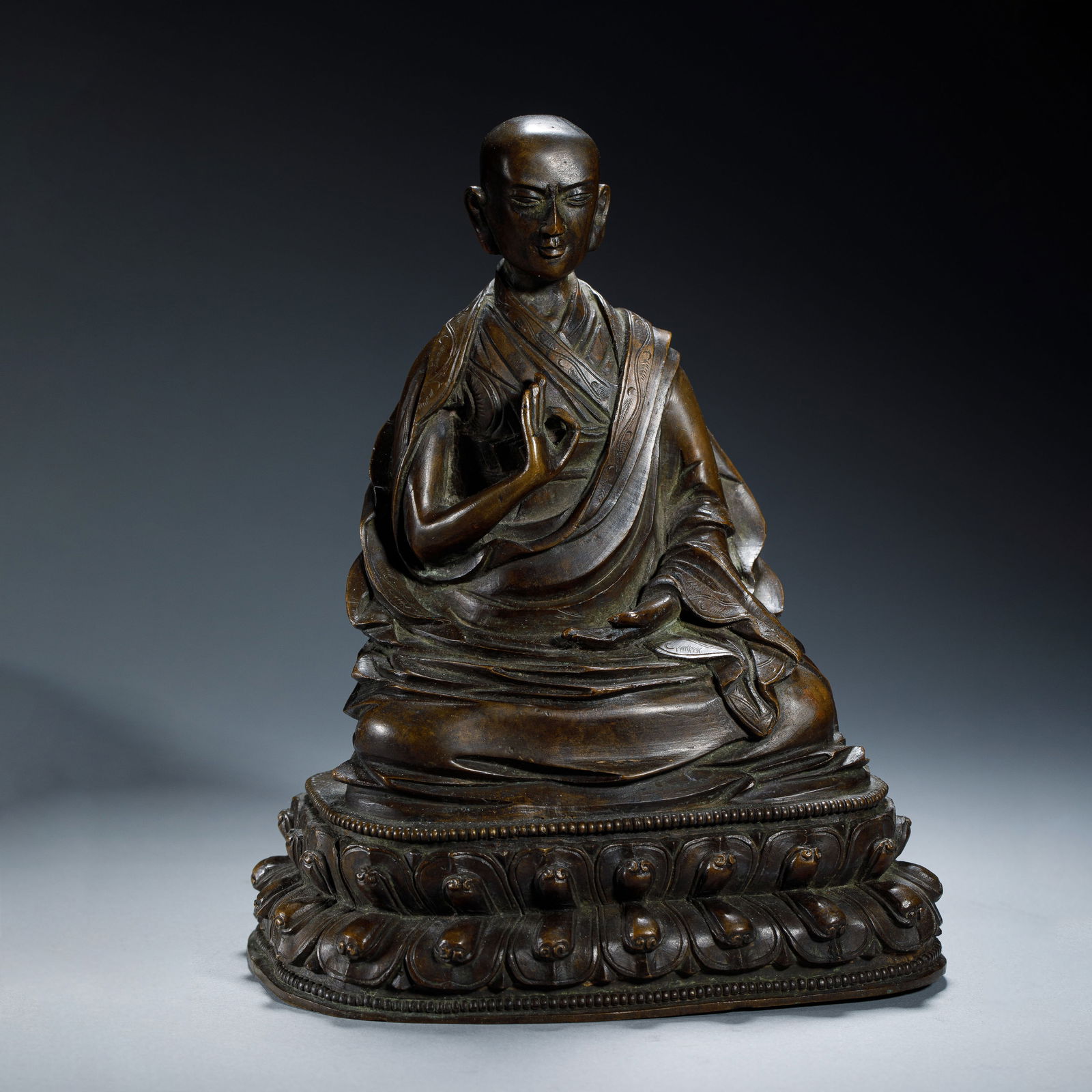 CHINESE SILVER-INLAID BRONZE TSONGKHAPA: Dimensions: L. 13.5 cm. H. 17 cm. Weight 2060 grams. This serene Chinese silver-inlaid bronze figure depicts Tsongkhapa, the revered Tibetan Buddhist master, seated in dhyanasana on a double lotus bas