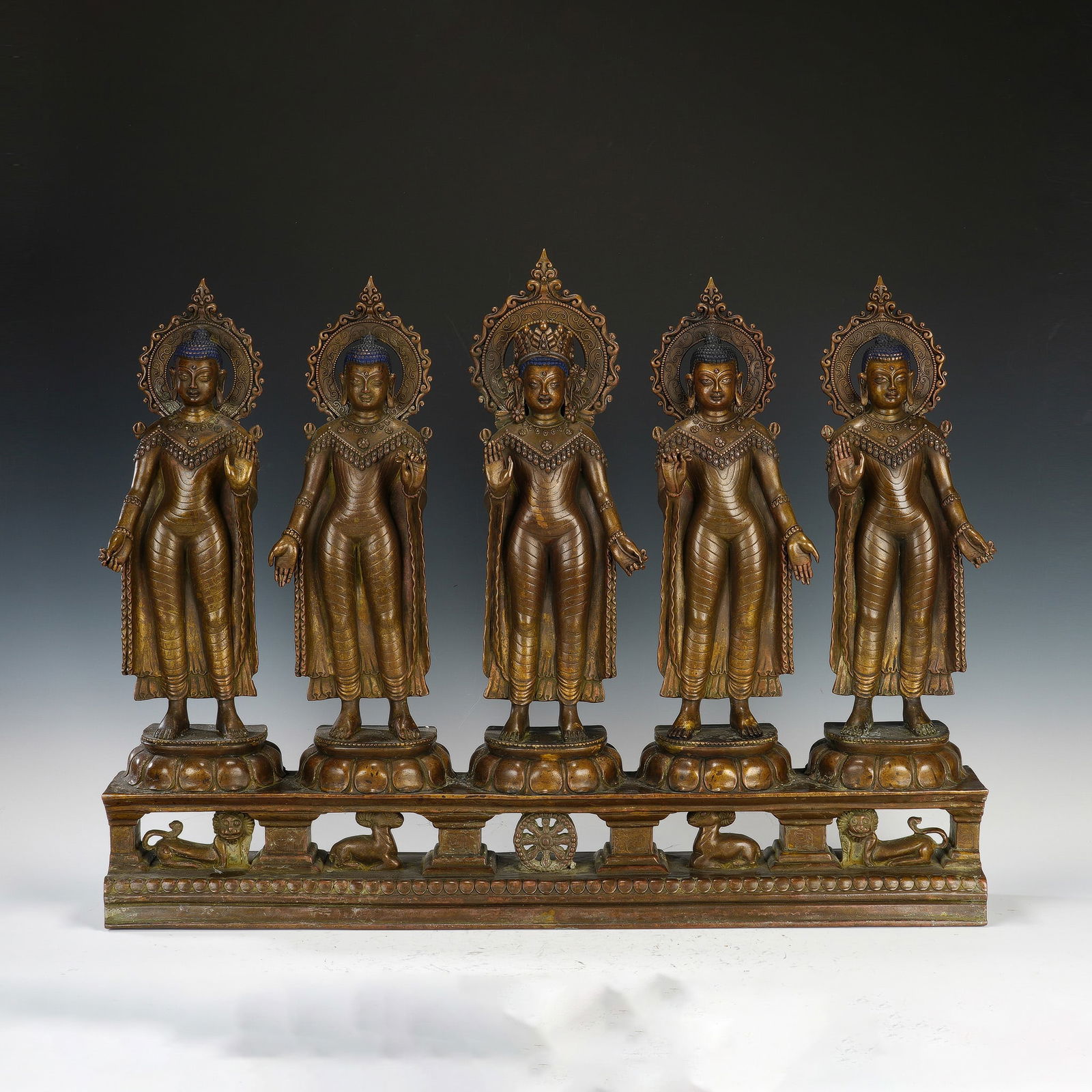 CHINESE BRONZE BUDDHA GROUP: Dimensions: 70x11x51.5 cm. Weight 23850 grams. This imposing Chinese bronze ensemble features five standing Buddhas, arranged in a row on a unified lotus base decorated with auspicious symbols includi