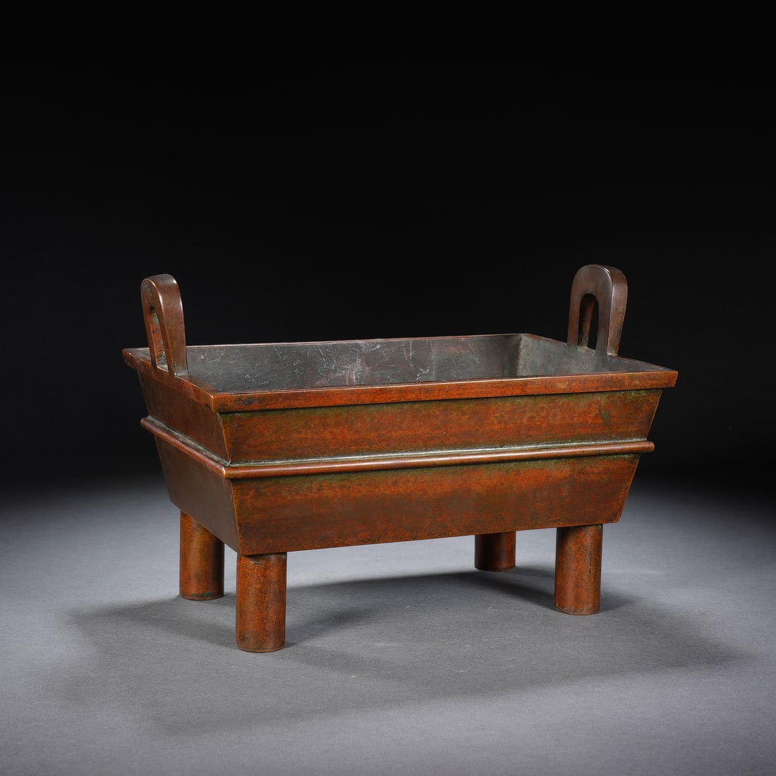 CHINESE BRONZE RECTANGULAR CENSER: Dimensions: 22x14x14.5 cm. Weight 1669 grams. This elegant Chinese bronze censer features a rectangular body, upright loop handles, and four sturdy cylindrical legs, with a subtle raised band defining
