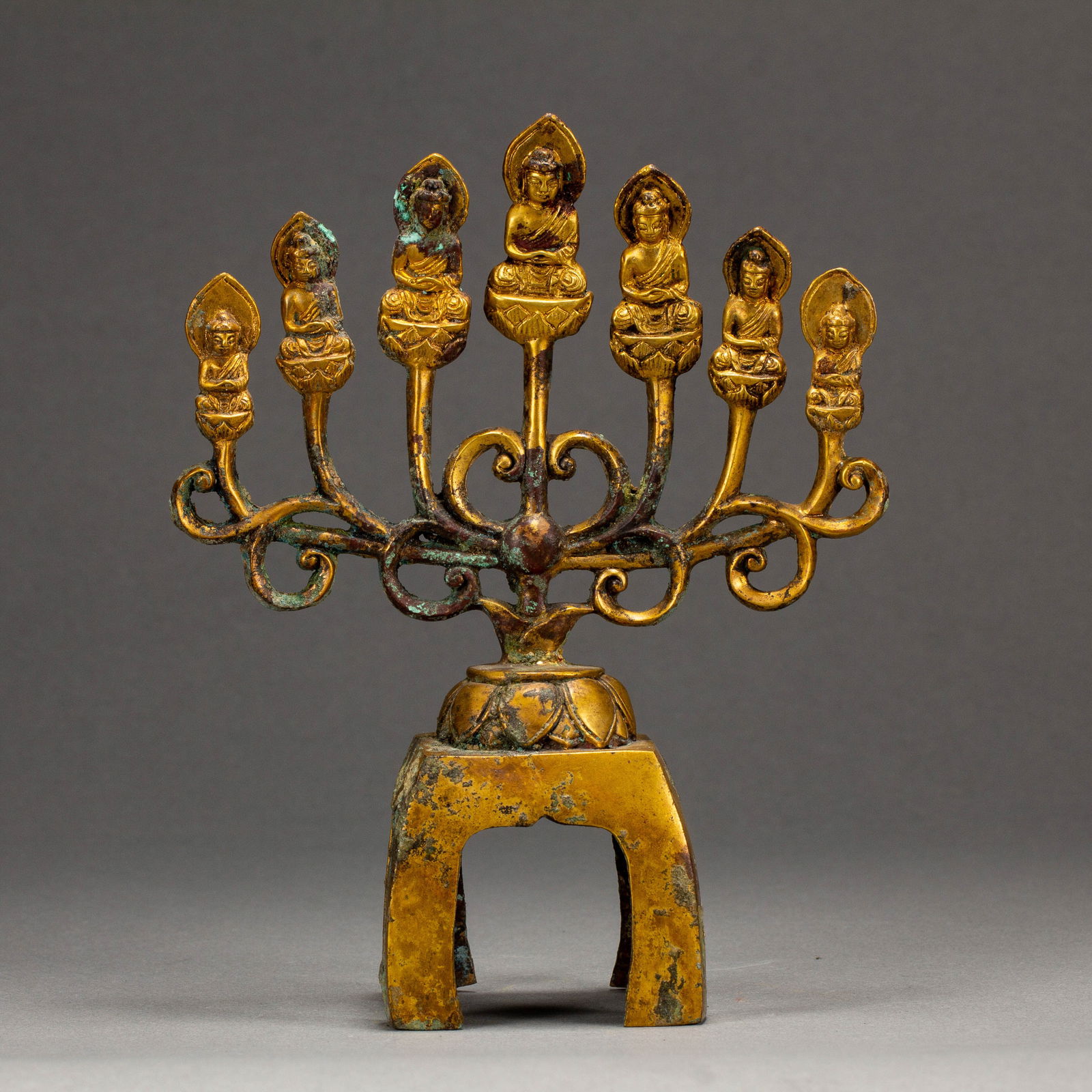 CHINESE GILT-BRONZE BUDDHA GROUP: Dimensions: L. 13 cm. W. 5.5 cm. H. 16.5 cm. Weight 330 grams. This exquisite Chinese gilt-bronze Buddha group features a central seated Buddha flanked by six smaller figures, each set atop