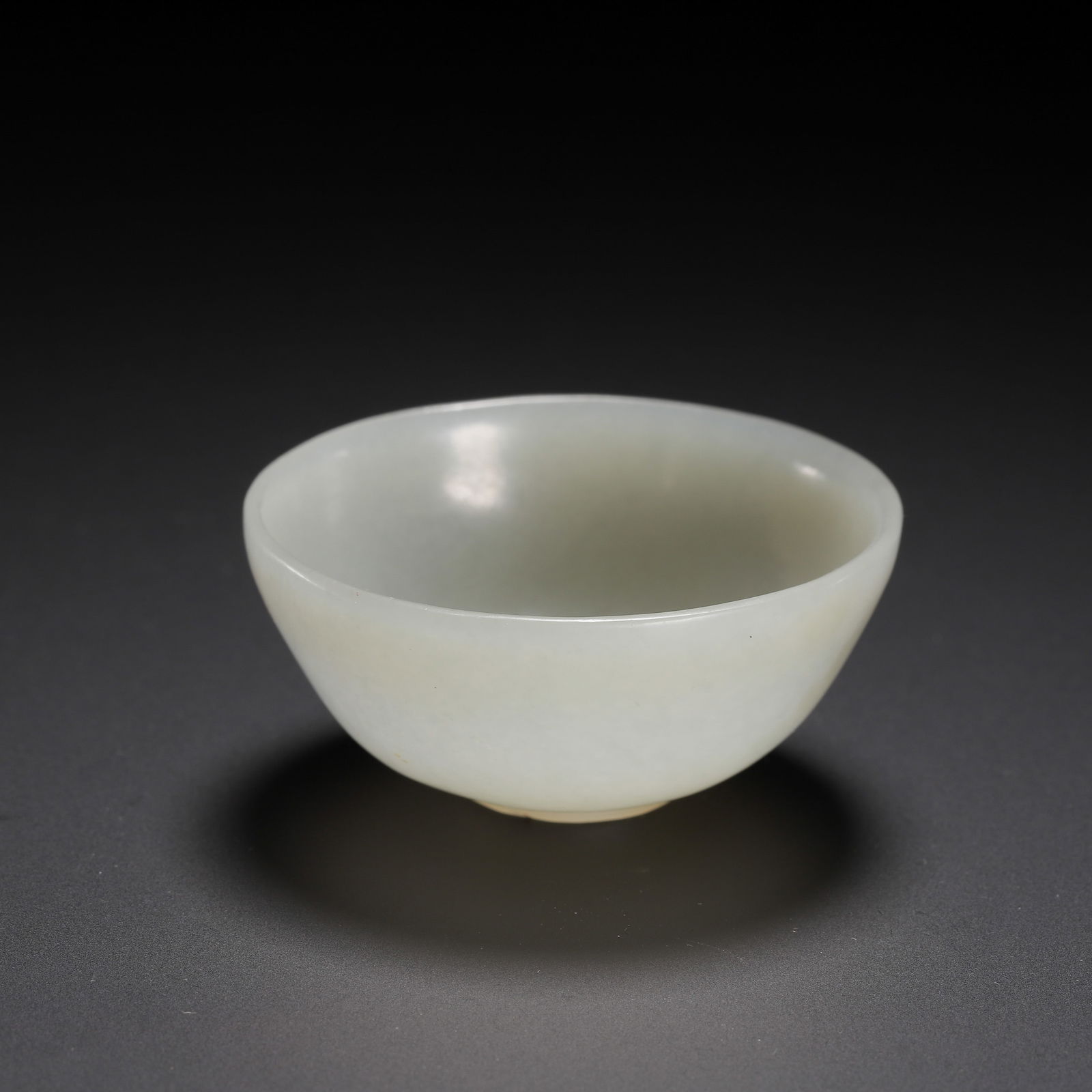 CHINESE HETIAN JADE BOWL: Dimensions: L. 5 cm. W. 5 cm. H. 2.5 cm. Weight 30 grams. This exquisite Chinese bowl is carved from translucent Hetian jade of a creamy celadon hue, featuring a smooth, rounded body and a delicate, f