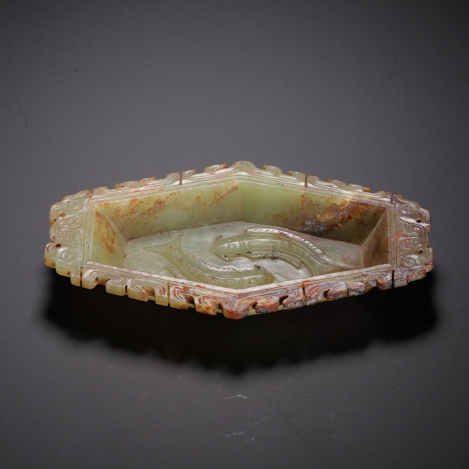 CHINESE ARCHAISTIC JADE DISH: Dimensions: L. 15 cm. W. 8 cm. H. 2.8 cm. Weight 180 grams. This elegant Chinese archaistic jade dish features a hexagonal form with a carved rim adorned with geometric and stylized taotie motifs. The