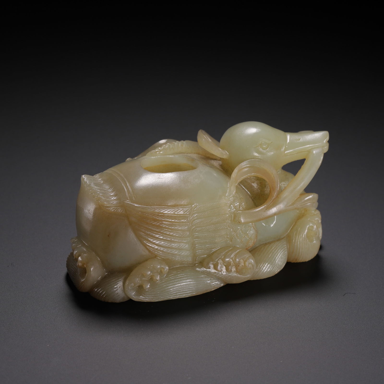 CHINESE HETIAN JADE DUCK WATER COUPE: Dimensions: L. 9.5 cm. W. 5 cm. H. 4 cm. Weight 250 grams. This exquisitely carved Chinese Hetian jade water coupe is shaped as a recumbent duck, its body rendered in smooth, pale celadon stone with s