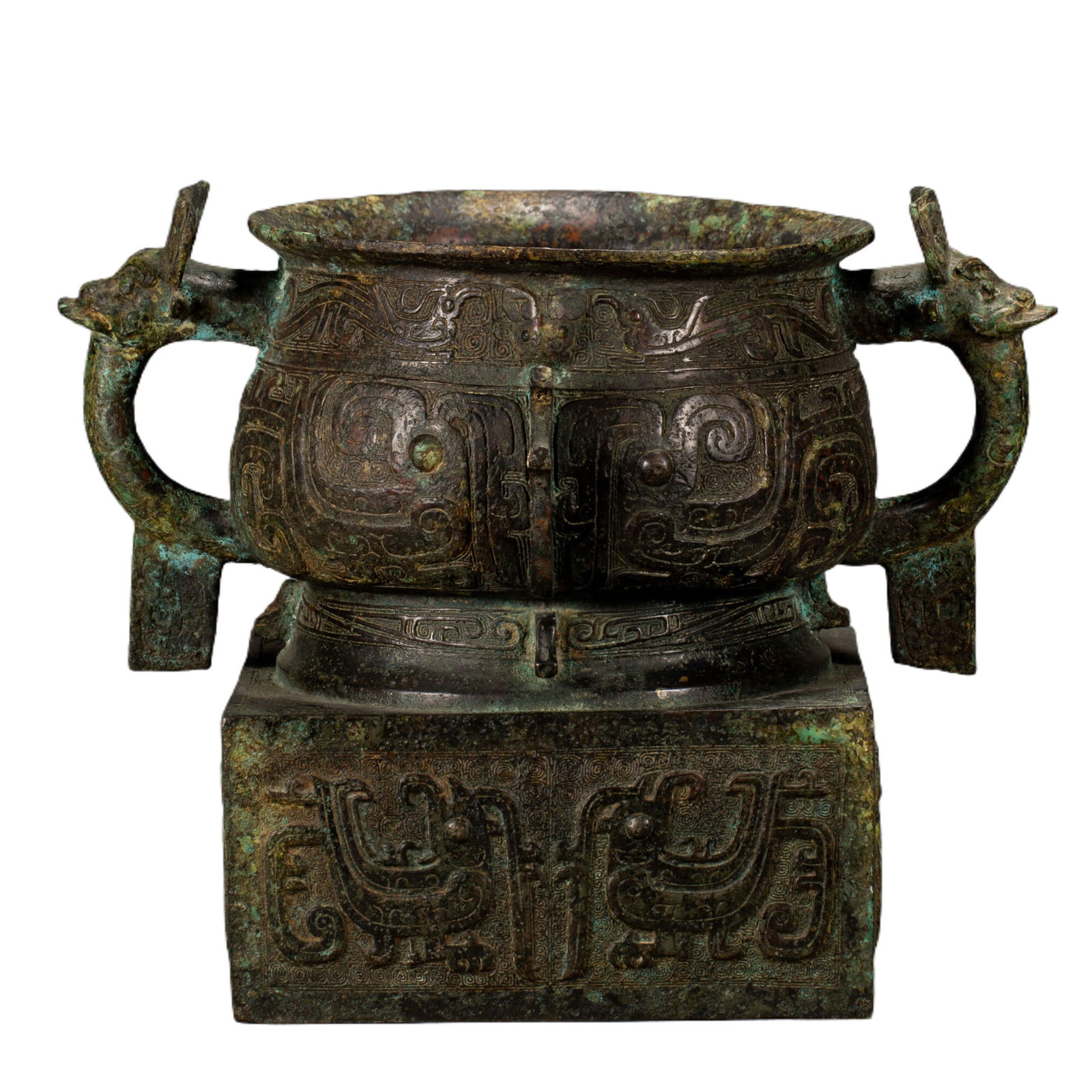 CHINESE BRONZE RITUAL CENSER: Dimensions: L. 30 cm. W. 20 cm. H. 24 cm. Weight 6280 grams. An imposing Chinese bronze ritual censer, raised on a square plinth with two dragon-headed handles flanking its wide, shallow body. The sur
