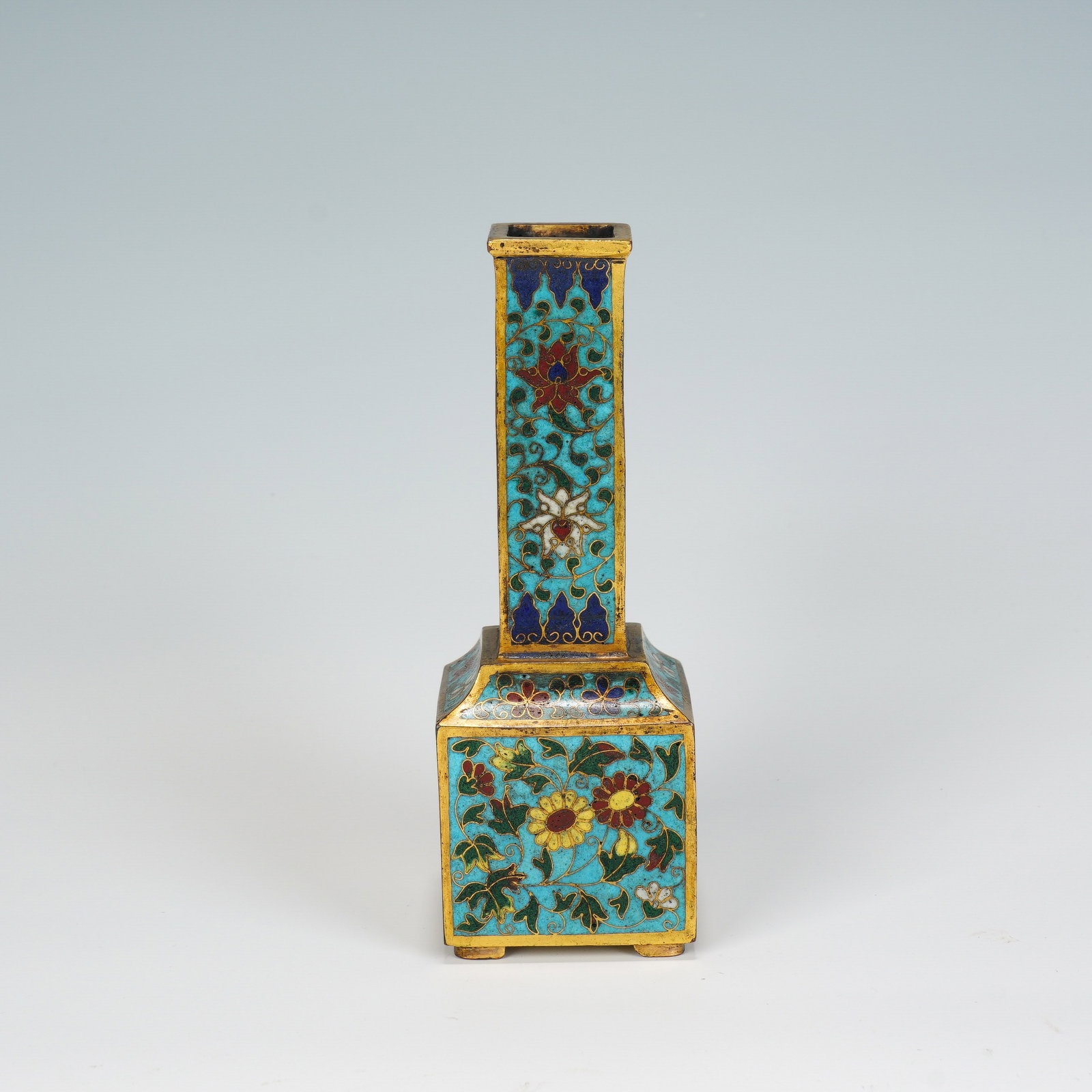 A CHINESE CLOISONNE SQUARE VASE: This elegant vase adopts a distinctive squared silhouette, with a slender tall neck rising from a wider cuboid lower body, all trimmed with polished gilded brass borders. Vibrant turquoise cloisonn? e