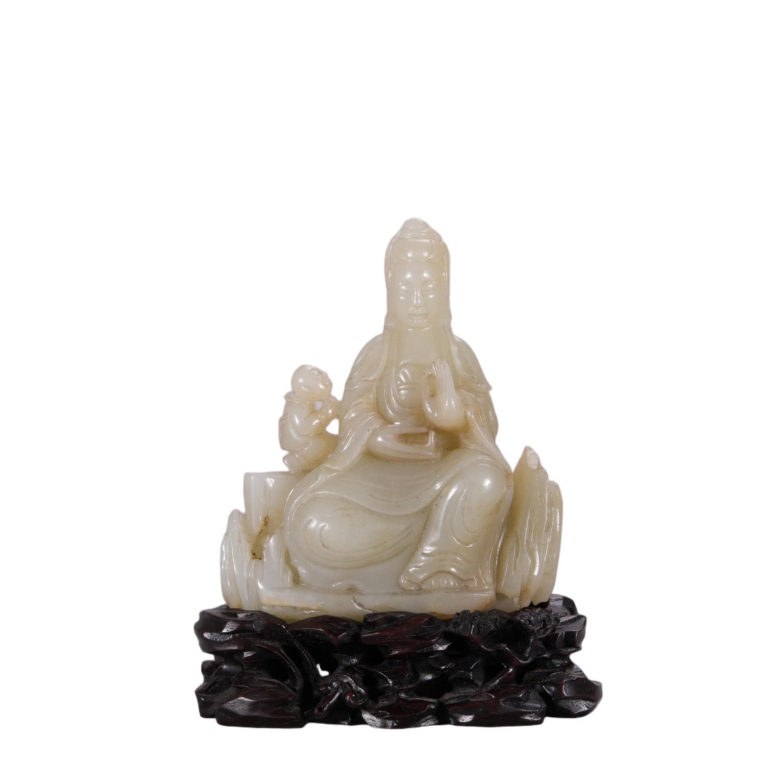 A CHINESE WHITE JADE GUANYIN WITH BOY GROUP: Carved from smooth pale white nephrite with subtle natural russet veining, this seated Guanyin group depicts the deity resting amid stylized rockwork, accompanied by the devotional boy Sudhana at her 