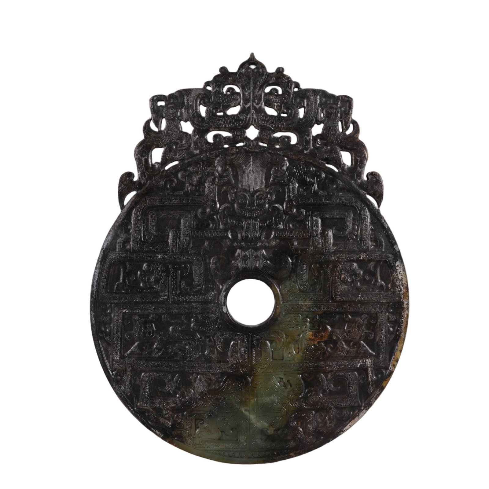 A CHINESE DRAGON CARVED JADE BI DISC: This ritual jade bi disc is crafted from nephrite with deep dark mineral patina interspersed with natural celadon and russet tones. Its flat surface is densely covered with symmetrical relief carvings