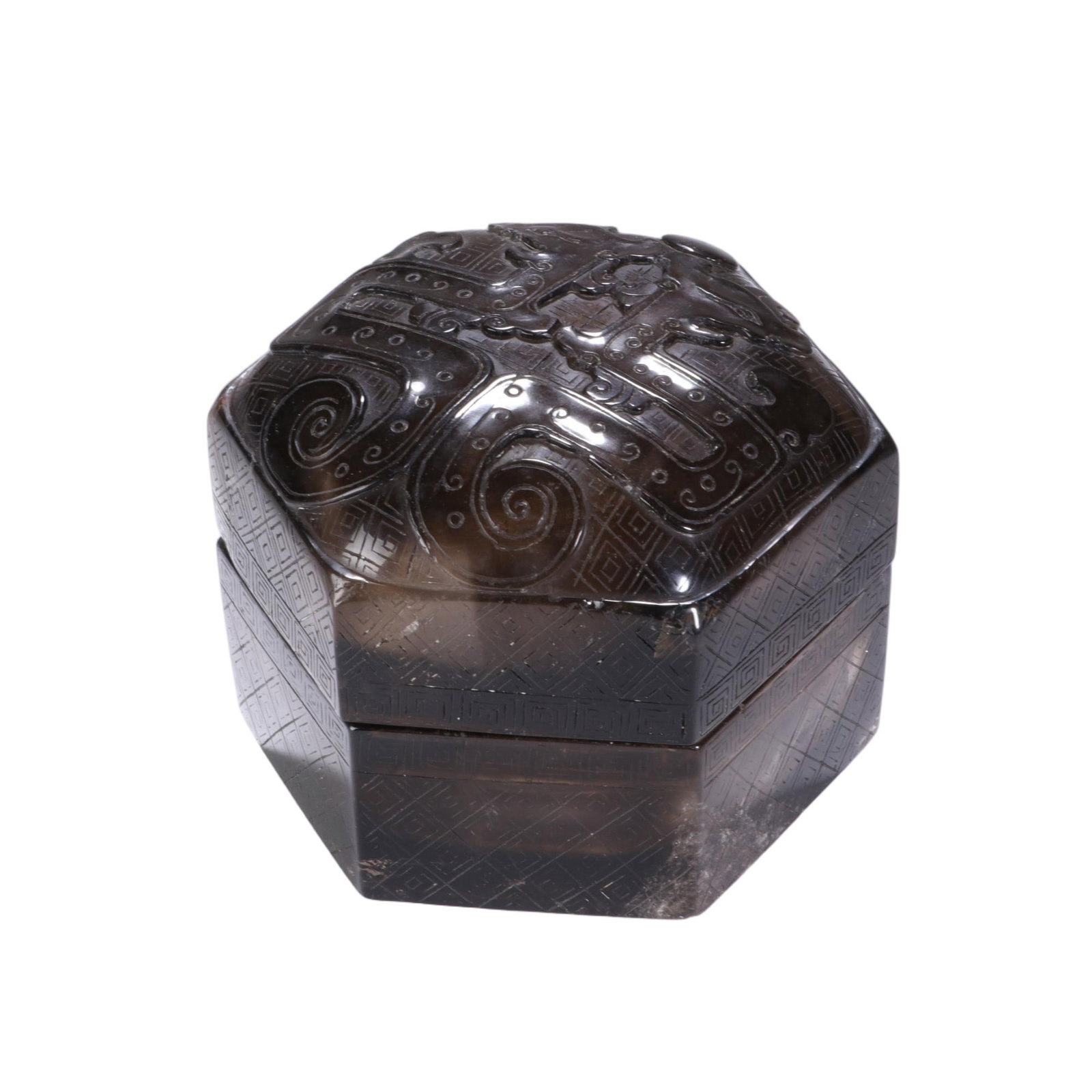 A CHINESE CRYSTAL LIDDED BOX: Measuring 7.6 cm in height and 9 cm in width, this hexagonal storage box is crafted from deep smoky crystal with appealing translucent tonal depth. Its domed lid carries raised archaistic scroll motif