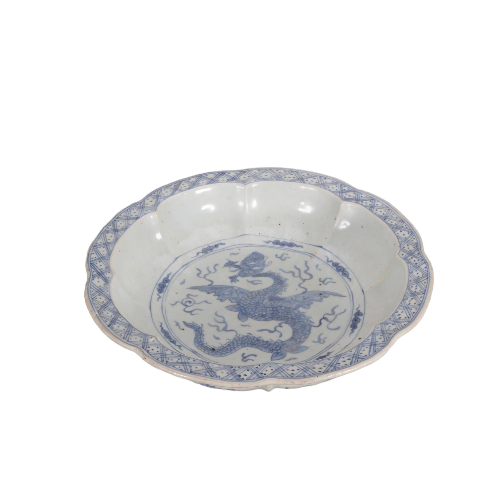A CHINESE BLUE AND WHITE DRAGON BASIN: This substantial lobed porcelain basin features a scalloped foliate rim with geometric diaper patterns lining the inner edge. The central medallion is vividly painted with a winged dragon amid curling