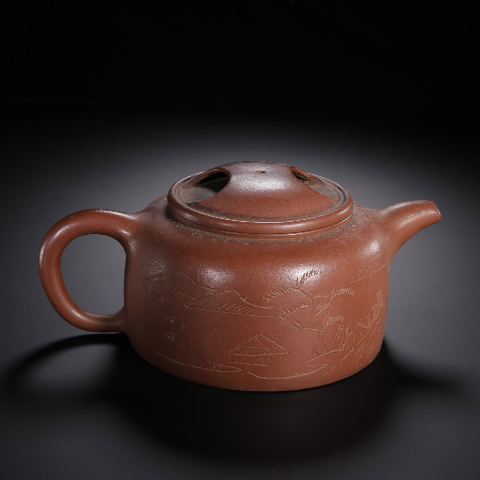 A CHINESE YIXING ZISHA TEAPOT: Standing 8 cm tall with a maximum width of 20 cm, this well-proportioned teapot is crafted from warm reddish-brown Yixing clay boasting a smooth, subtly matte natural finish. Its stout cylindrical bod