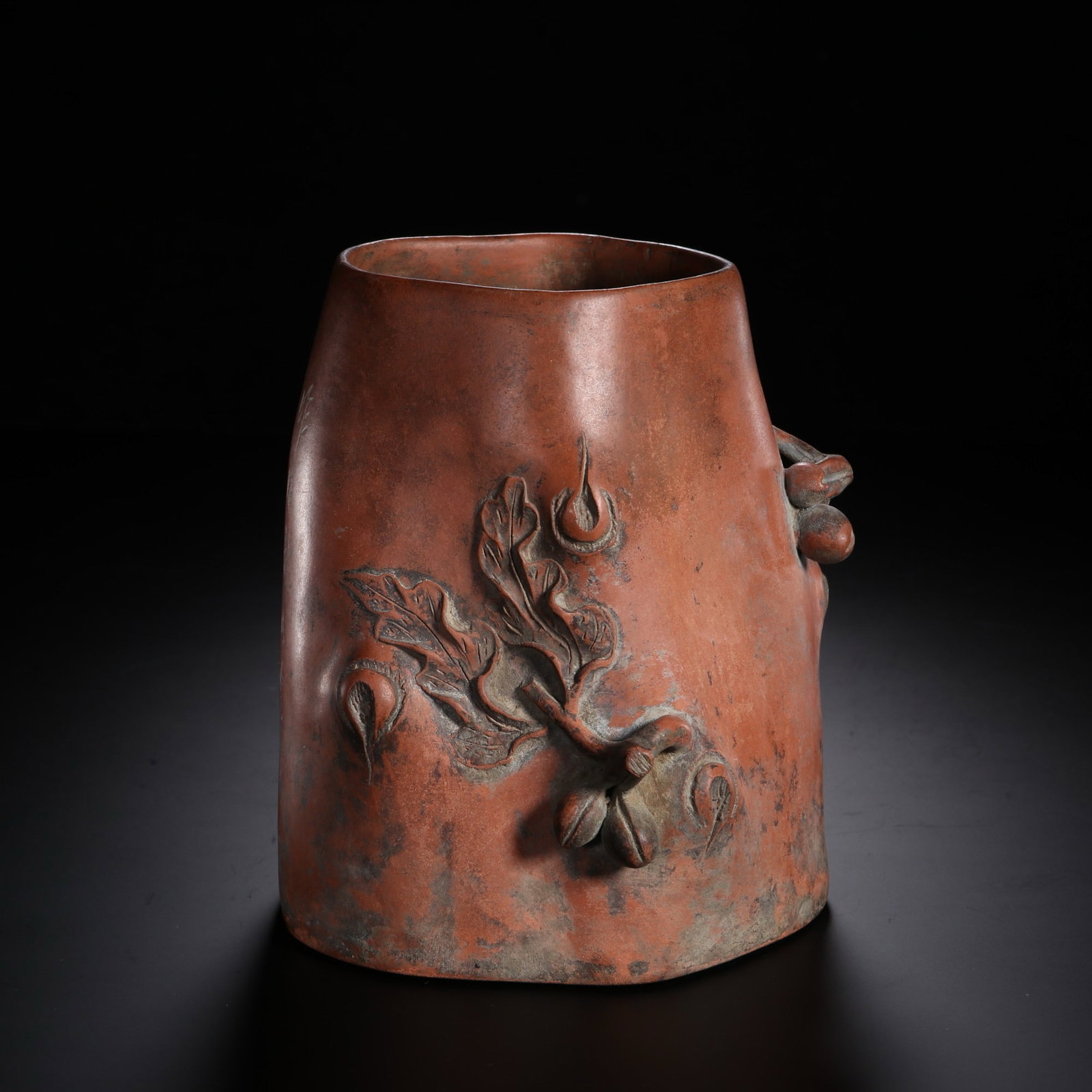 A CHINESE PEACH MOTIF ZISHA BRUSH POT: Standing 15 cm tall, 12.5 cm wide and weighing 650 grams, this brush pot is handcrafted from warm reddish aged Yixing zisha clay with natural tonal variations and gentle wear patina across its trunk-s