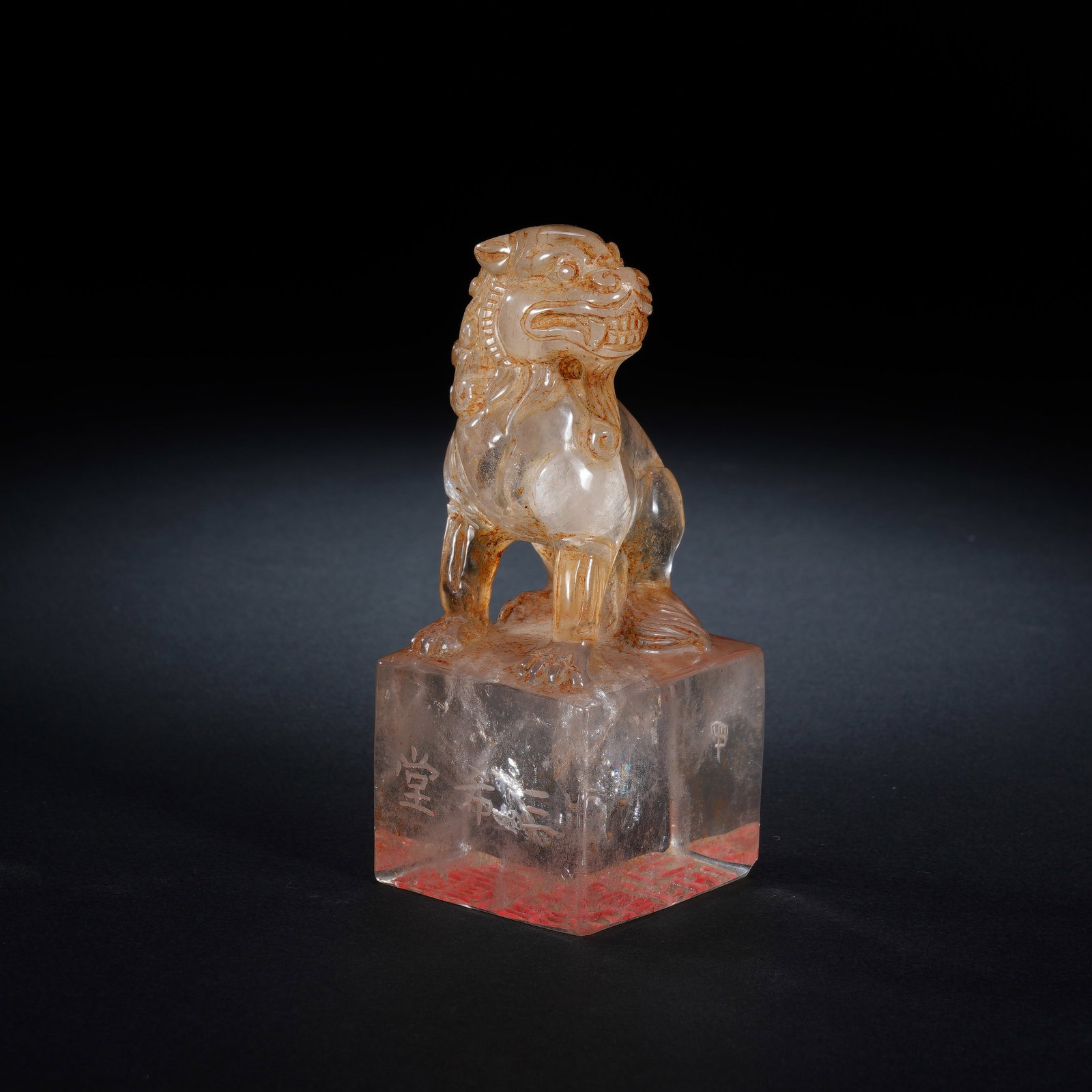 A CHINESE ROCK CRYSTAL LION KNOB SEAL: Crafted from translucent natural rock crystal with faint warm ochre internal veining, this seal consists of a solid squared shaft topped by a meticulously sculpted seated guardian lion knob. The lion 