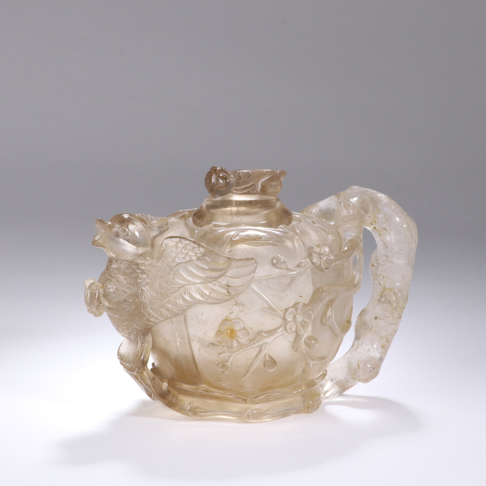 A CHINESE CRYSTAL PHOENIX EWER: Standing 11 cm tall and 15 cm in width, this graceful ewer is masterfully carved from translucent rock crystal that bears faint warm natural mineral inclusions throughout its body. A finely detailed p