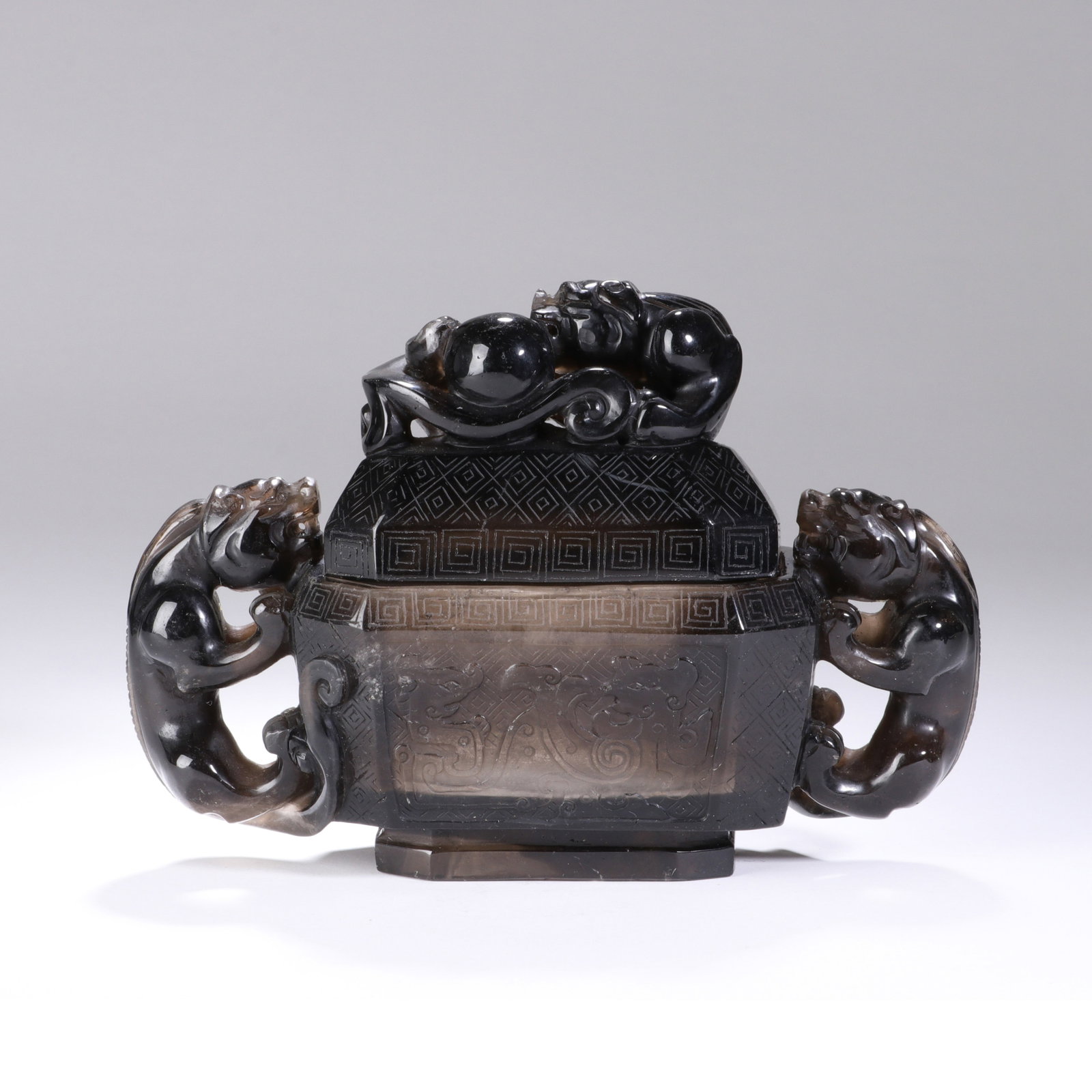 A CHINESE CRYSTAL DRAGON PATTERN CENSER: Standing 11.8 cm tall with a maximum width of 17 cm, this elaborate censer is carved from graded smoky crystal showcasing attractive shifts between deep shadowed tones and lighter translucent sections
