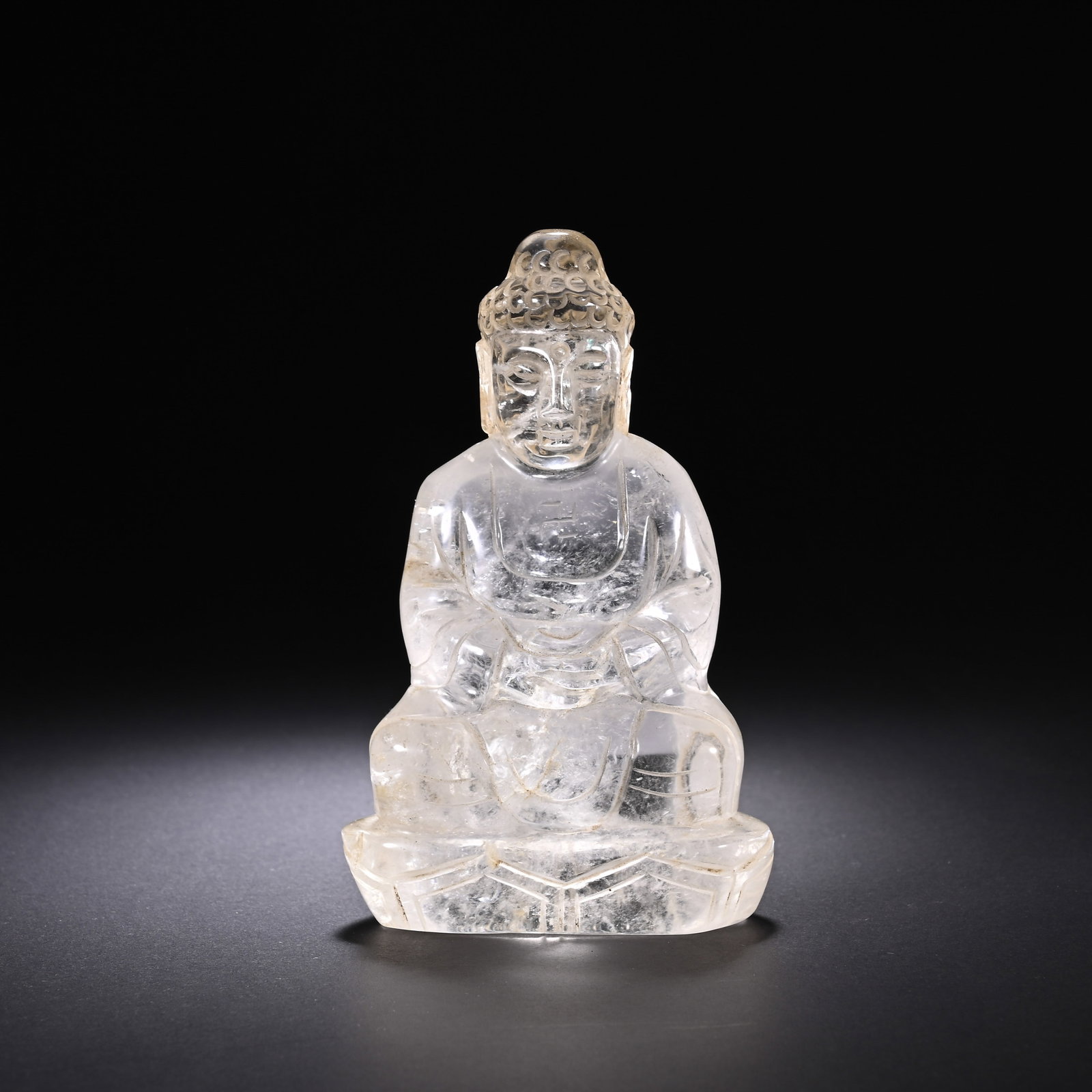 A CHINESE ROCK CRYSTAL BUDDHA: Standing 12 cm high and 7.5 cm across, this serene Buddha sculpture is meticulously carved from natural transparent rock crystal that features faint inherent mineral veils and subtle internal inclusio