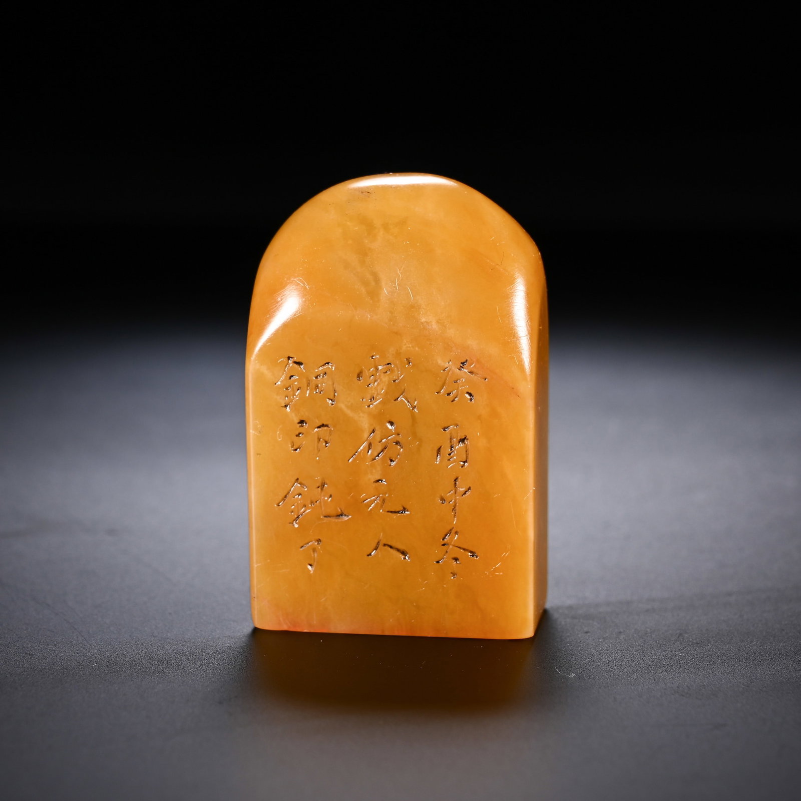 A CHINESE TIANHUANG STONE SEAL: Measuring 4.5 cm in height and 2.8 cm in width, this compact solid seal is hewn from warm amber-toned Tianhuang stone showcasing subtle natural internal veining beneath a glossy, well-worn polish. Its