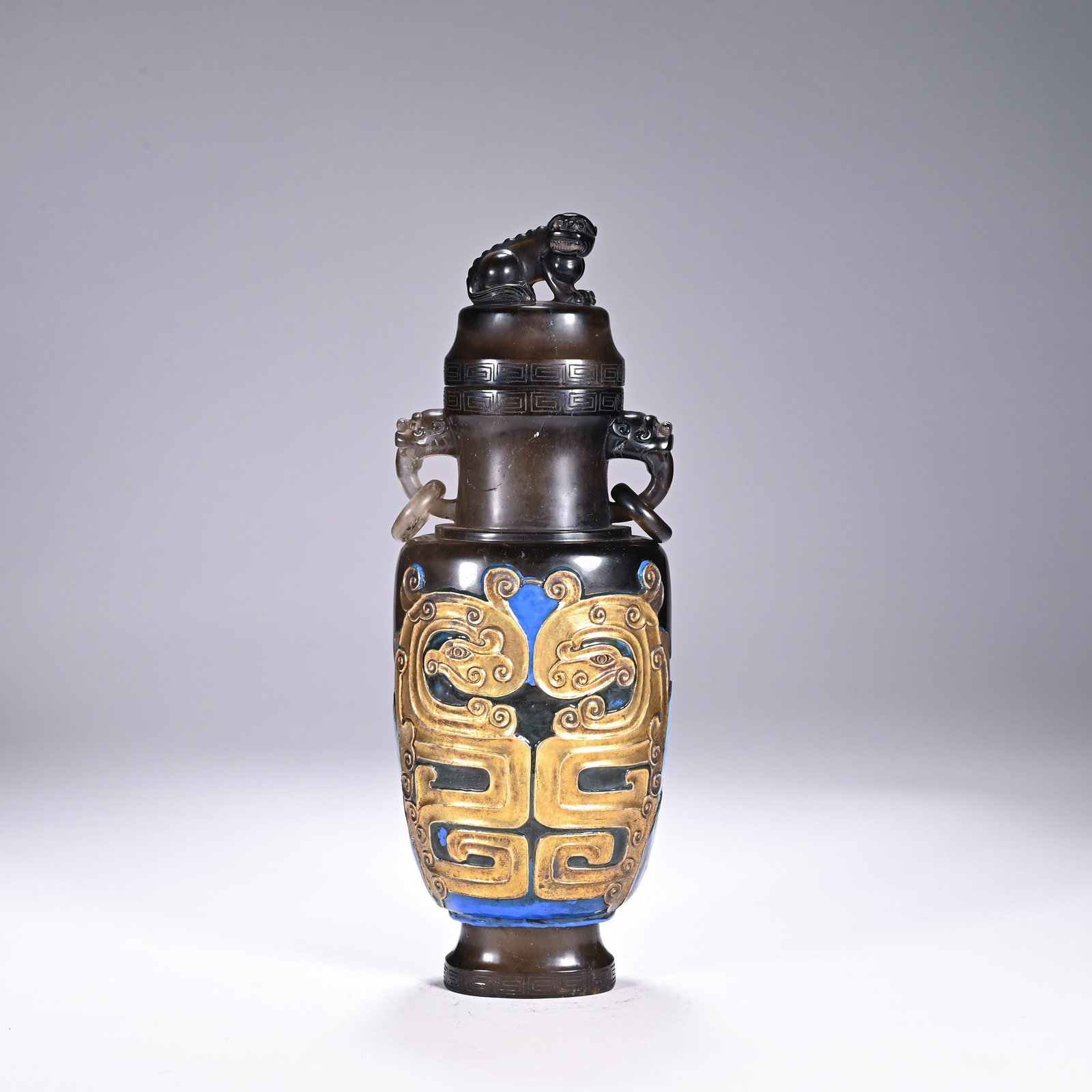 A CHINESE ROCK CRYSTAL VASE: Standing 24.5 cm tall and measuring 8.5 cm across, this stately crystal vase exhibits warm smoky tonal variations across its polished crystalline body. Its fitted lid is crowned by a crouching mythica