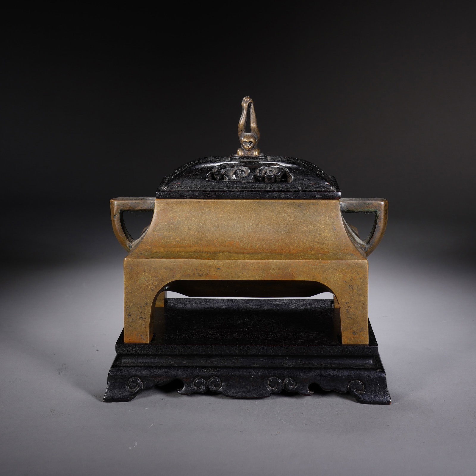 A CHINESE SQUARE BRONZE CENSER: This elegantly proportioned square censer is finely cast from warm-toned bronze with naturally mottled aged patina across its smooth exterior. Symmetric flat loop handles extend from both sides of the