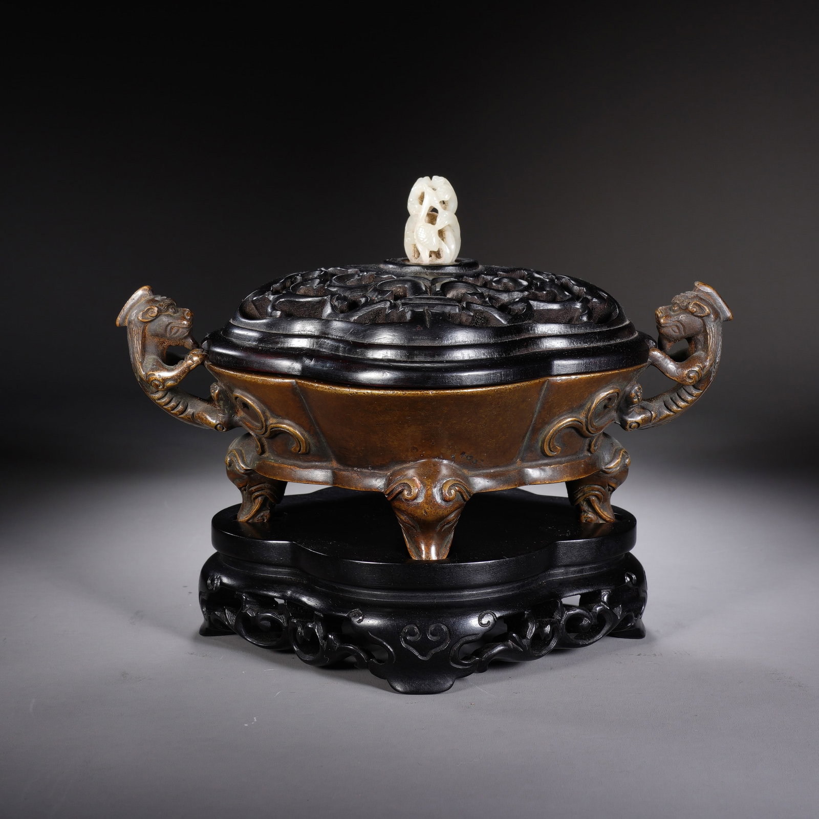 A CHINESE BRONZE CHILONG HANDLED CENSER: Crafted from patinated bronze, this elegant censer features elaborately sculpted chilong dragon handles on both sides, supported by four gracefully shaped scrolling feet. A finely pierced dark hardwoo
