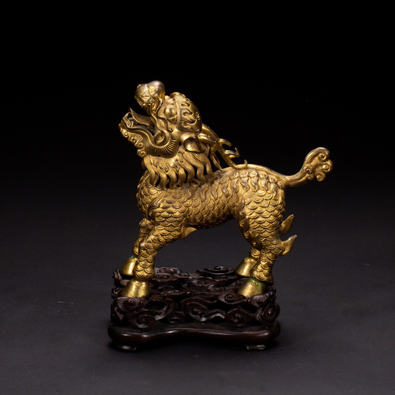 A CHINESE GILT BRONZE QILIN BEAST: Weighing 910 grams, this splendid mythical beast sculpture measures 15.5 cm long, 7 cm wide and 18 cm tall. Crafted from gilded bronze, the qilin boasts intricately chased layered scales covering its 